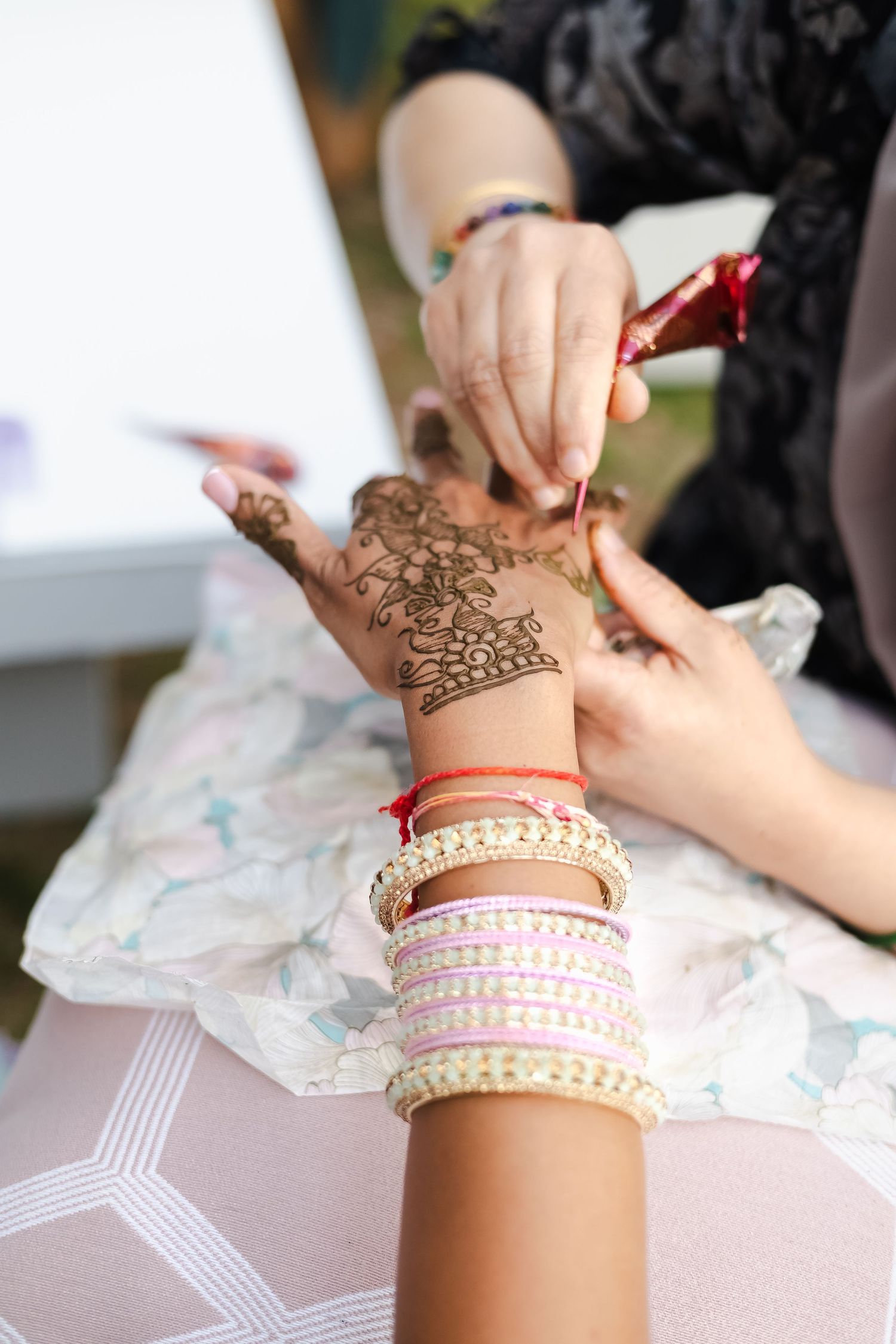 Close-up sequence showing the application of intricate henna designs and bangles on a person's wrist.