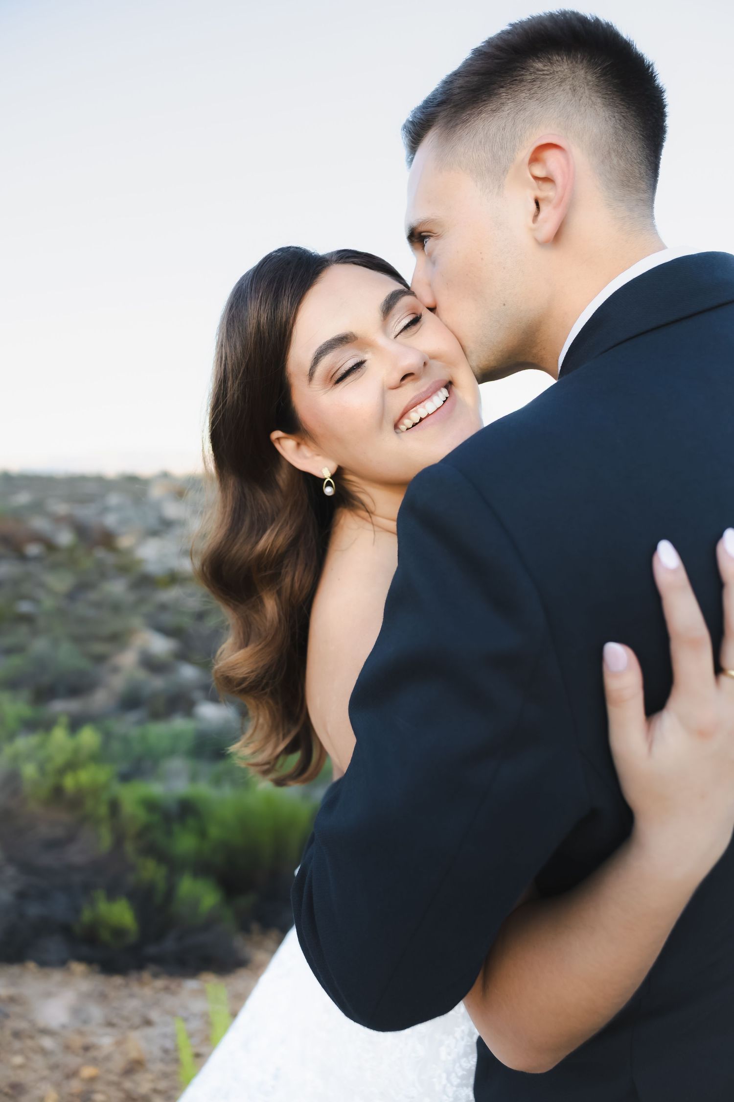 Intimate wedding couple moment captured against natural desert backdrop during golden hour.