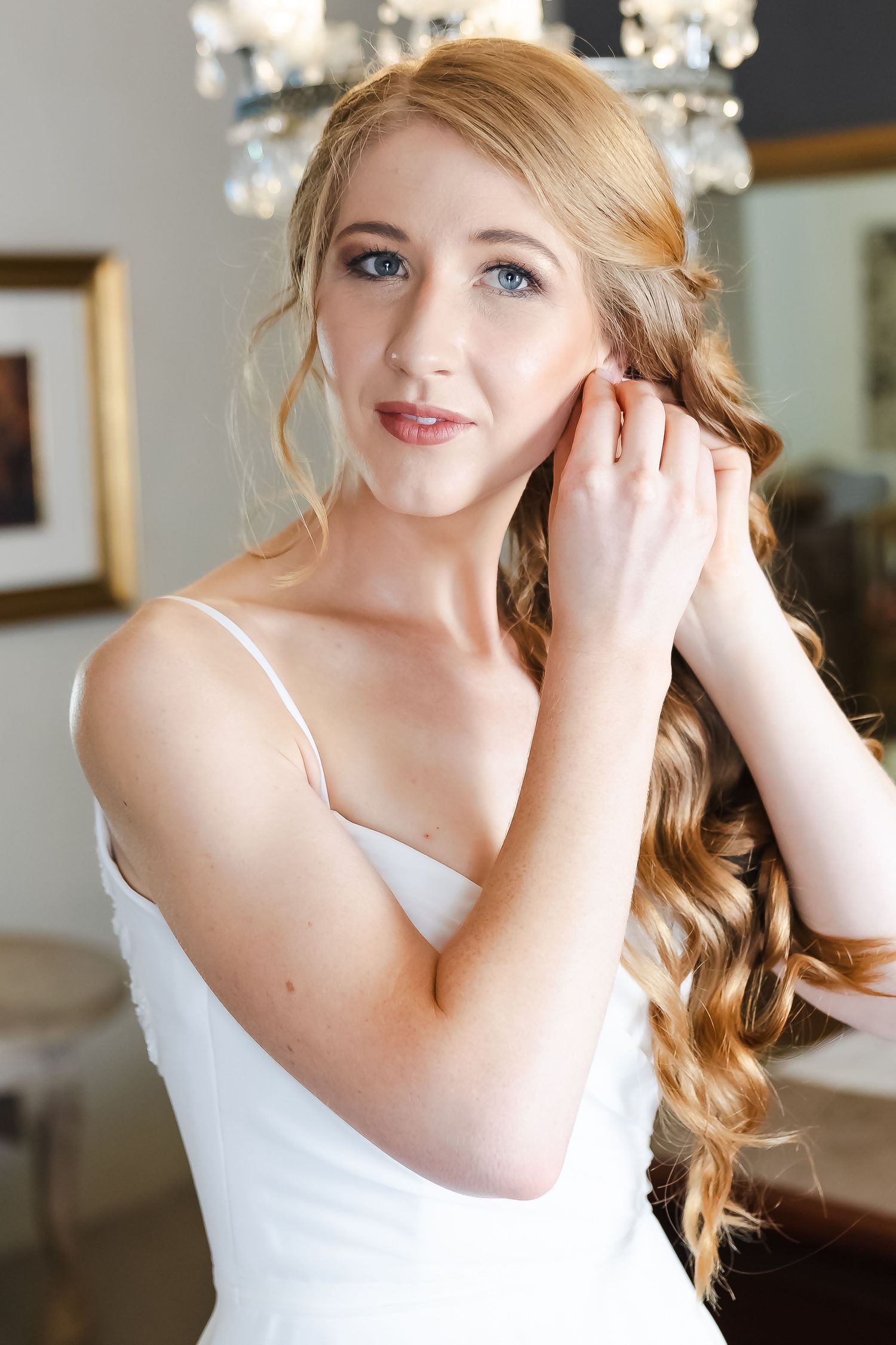 Close up portrait of a bride with elegant blonde curls and natural makeup getting ready.
