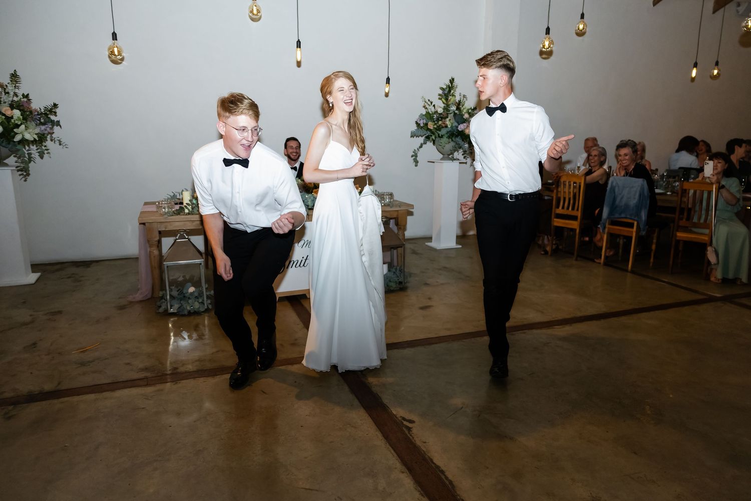 Wedding guests dancing and celebrating on a rustic venue dance floor.