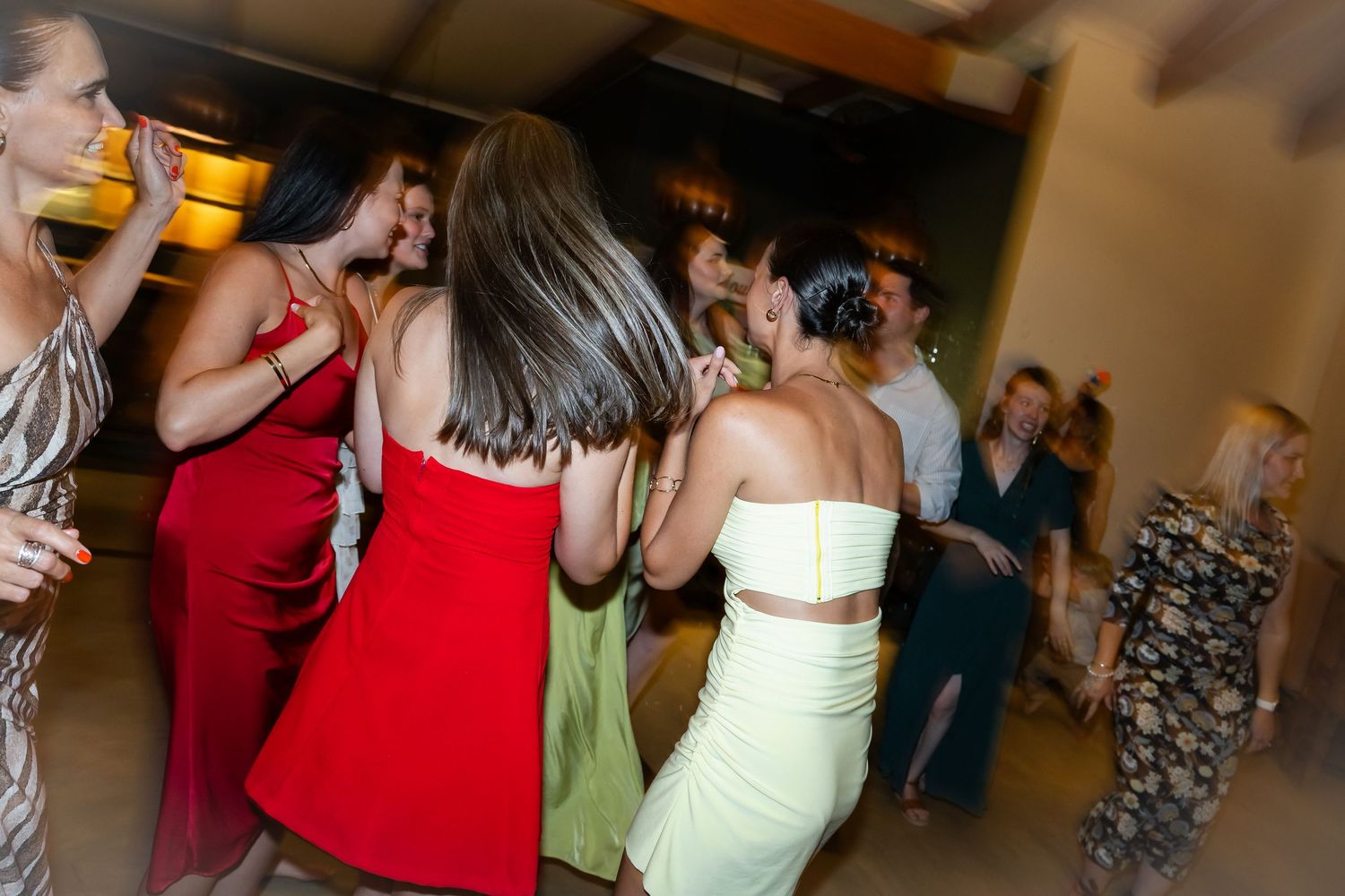 Party guests dancing and socializing at an indoor reception event.