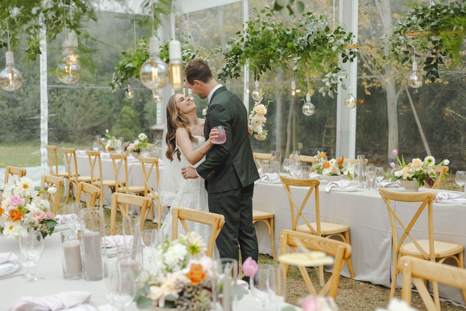 Elegant outdoor wedding reception setup with wooden chairs and floral centerpieces.