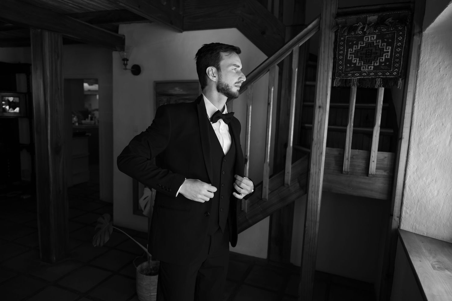 A series of moody black and white photos showing a figure in a suit standing near wooden stairs.