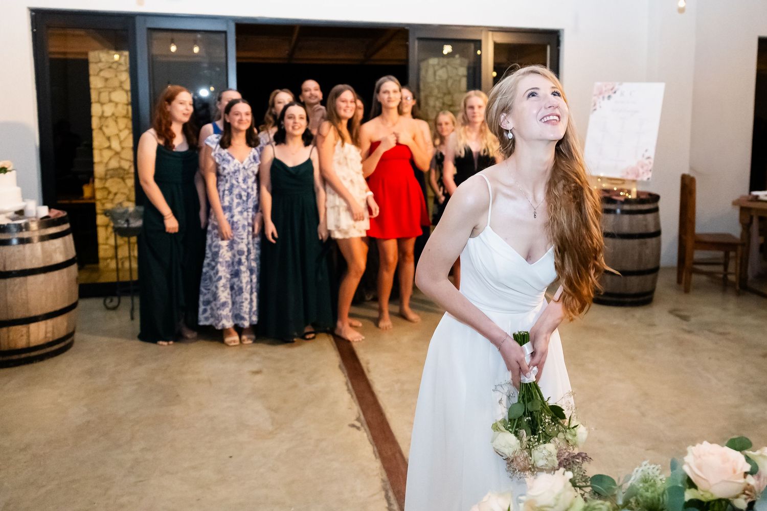 A joyful celebration unfolds at a rustic barn wedding venue with guests gathered around a dance floor.