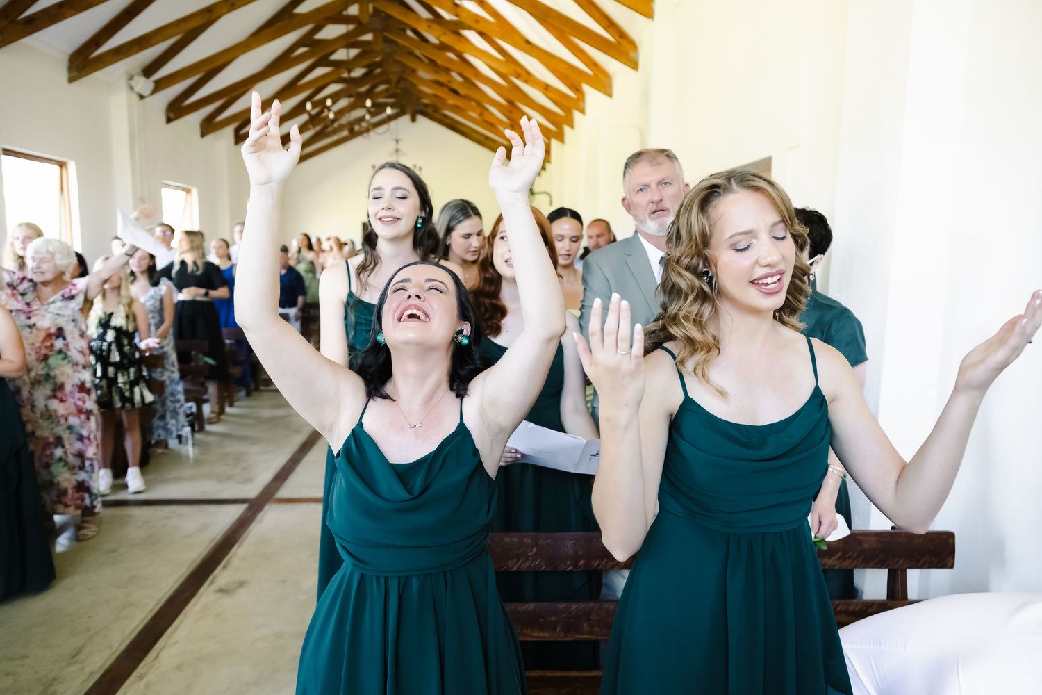 A group of bridesmaids in navy blue dresses react with joy and excitement during a wedding celebration.