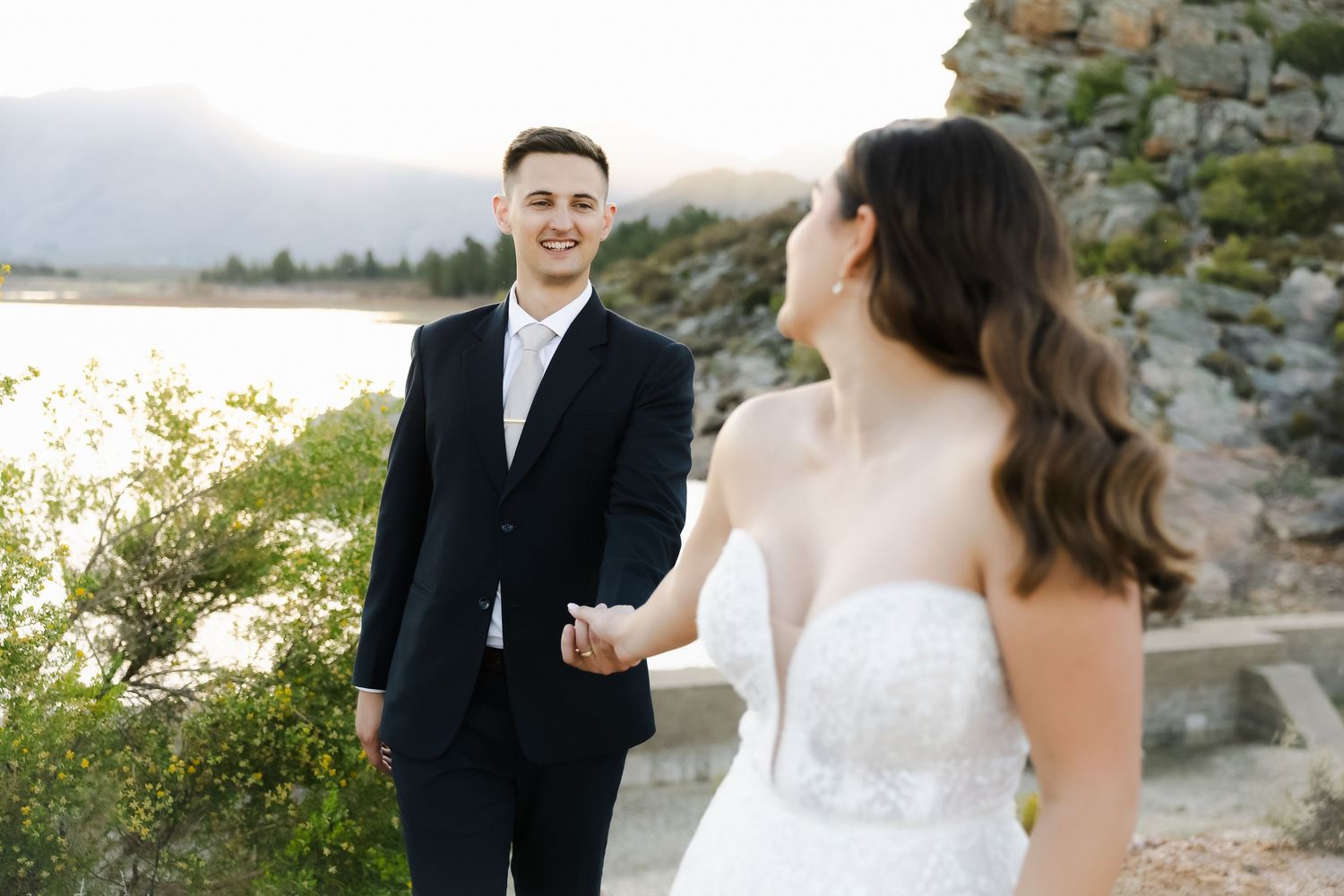 A candid wedding portrait showing a couple sharing a joyful moment outdoors.