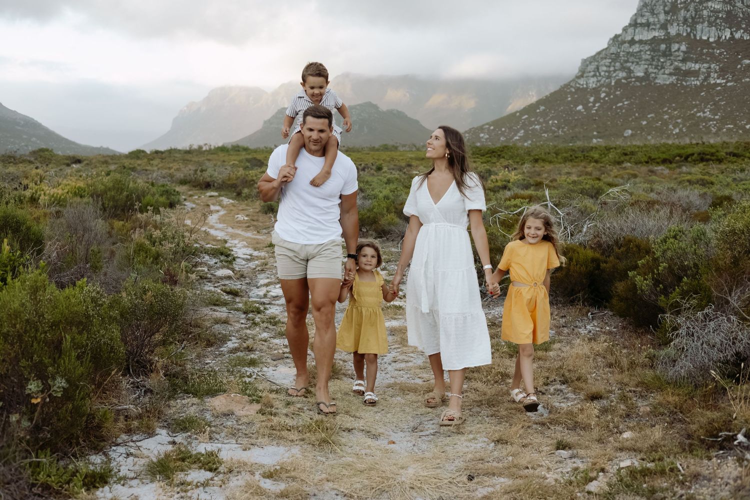Family walking together on mountain trail at sunset.