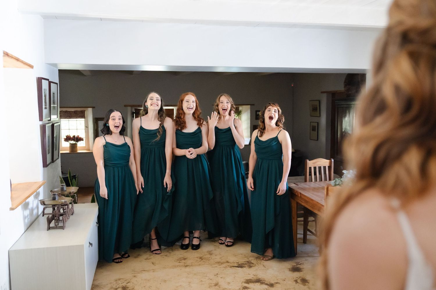 Row of bridesmaids in teal dresses stand together during wedding preparations.