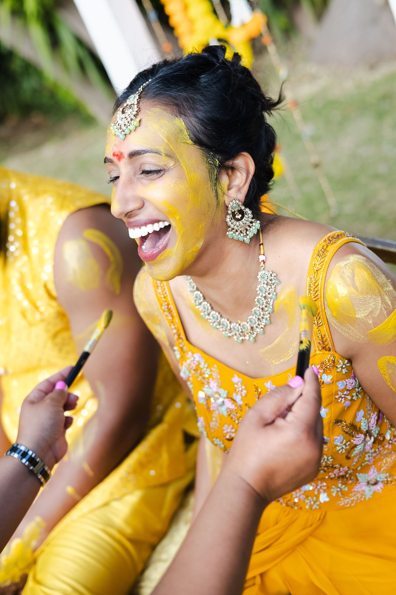 A joyful moment captured in a series of close-up shots showing laughter while wearing yellow traditional attire and jewelry.