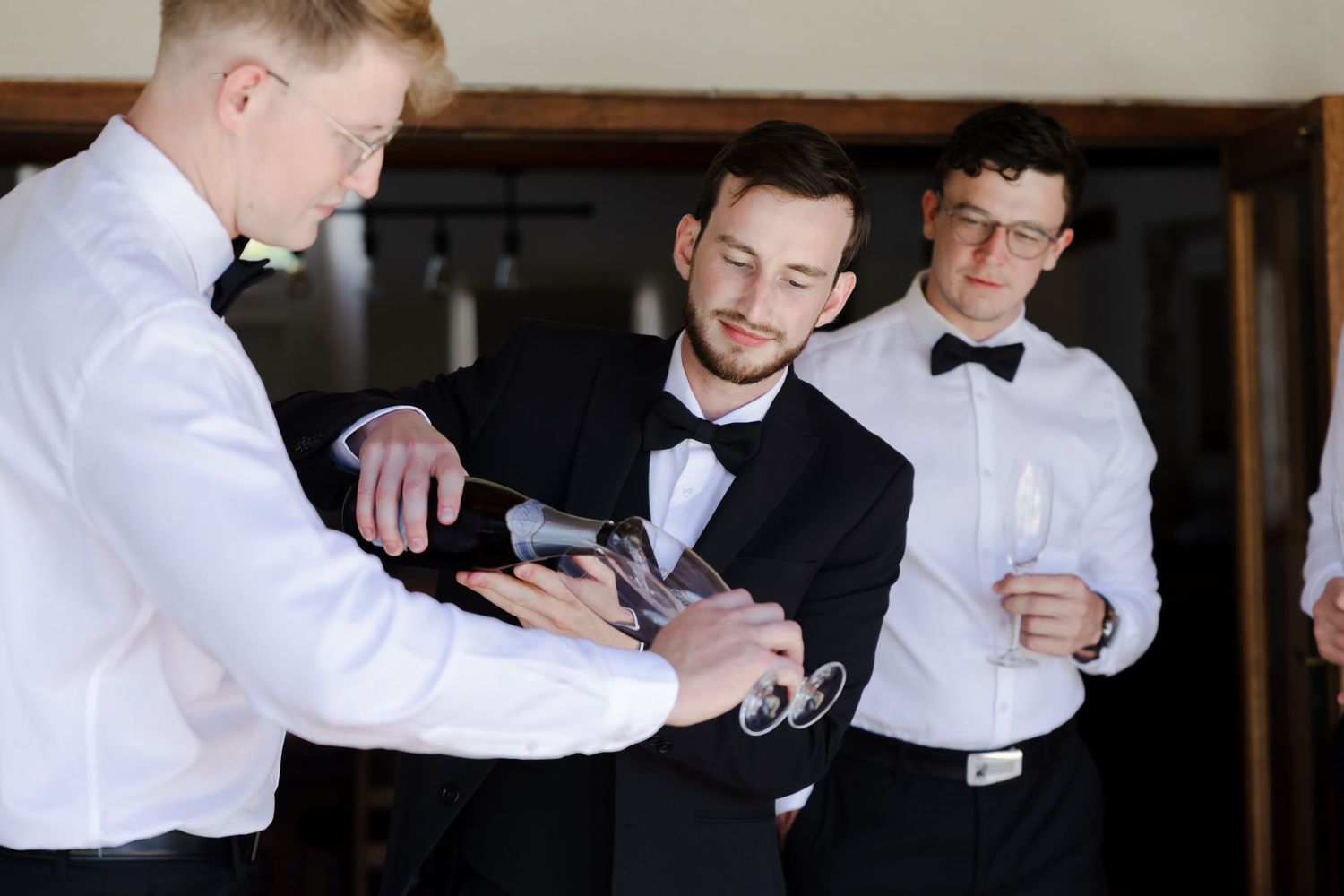 Several people in formal attire gathered together checking their phones and watches.