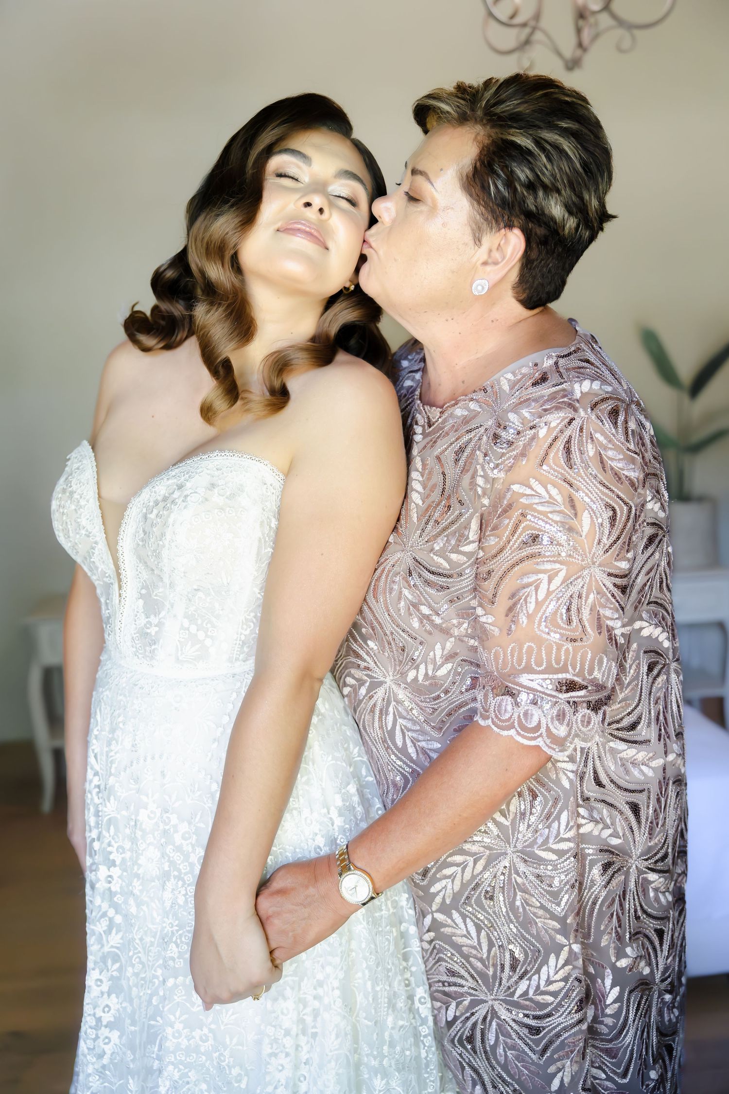 Two people in formal attire share an emotional embrace during what appears to be a wedding celebration.