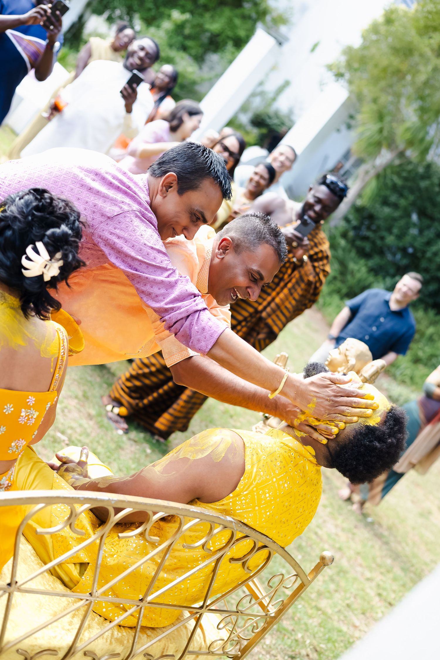 Person in yellow dress and pink top performing a cultural dance outdoors during a celebration.
