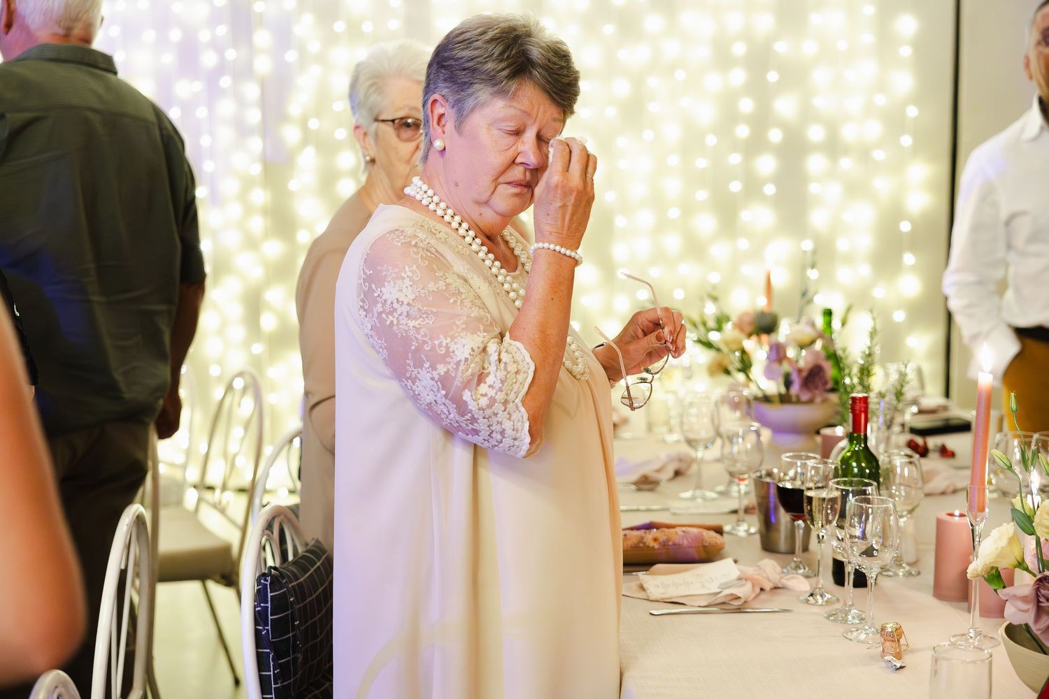 Wedding reception tables decorated with twinkle lights and elegant place settings create a romantic atmosphere.