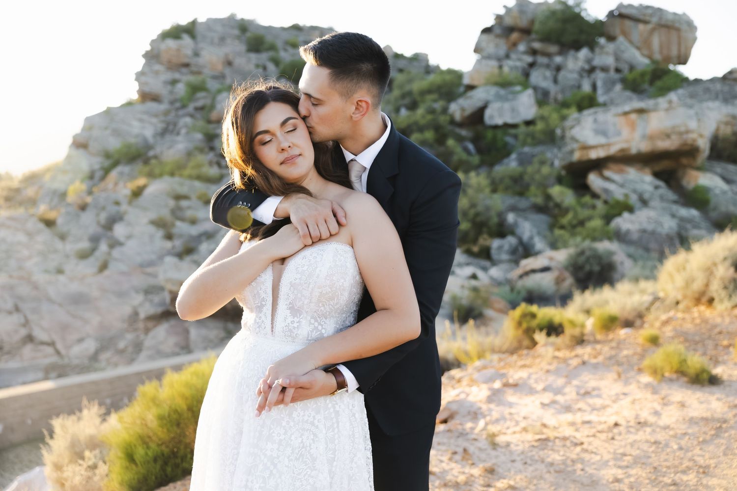 An intimate moment between newlyweds against a backdrop of desert rocks and mountains.