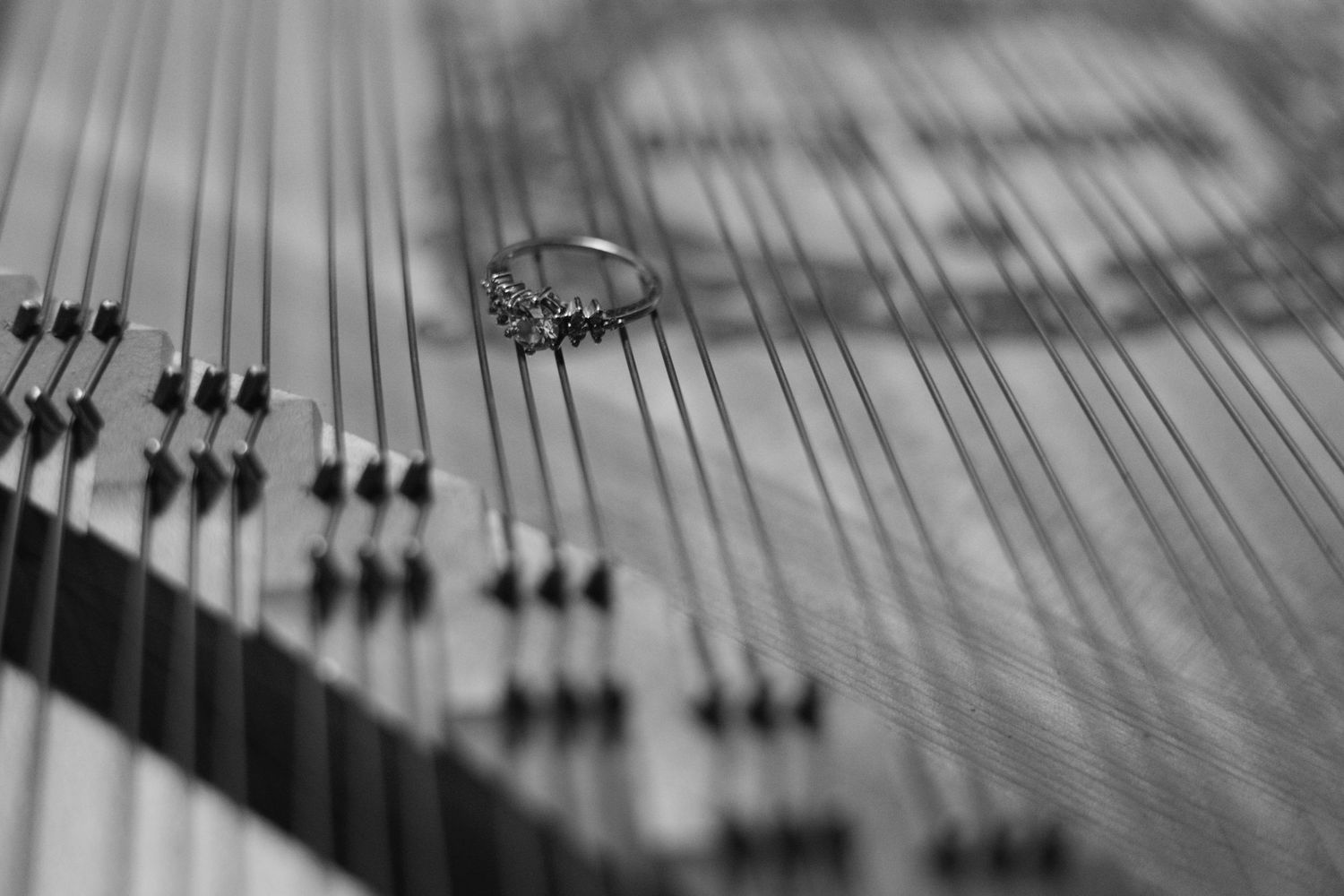 Close-up view of piano strings and hammers inside an upright piano in black and white.