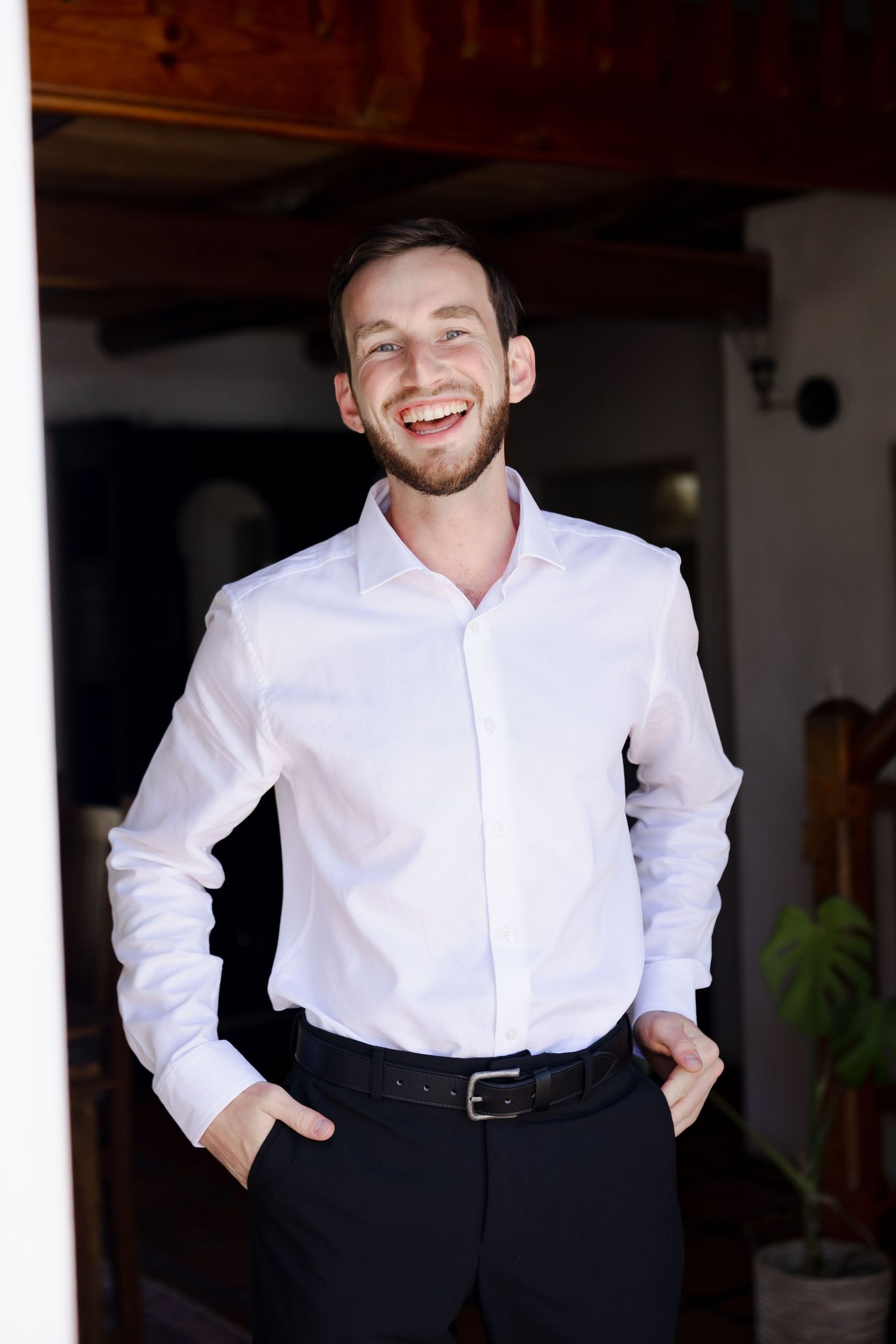 A series of formal portraits showing someone in a crisp white dress shirt and dark pants against a dark background.