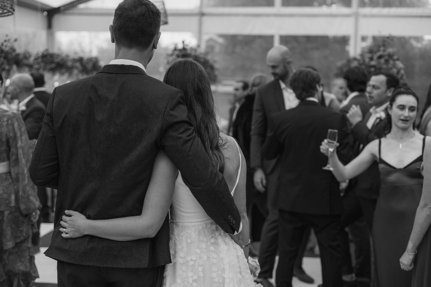 Black and white photo captures dancing and celebration at an elegant wedding reception.