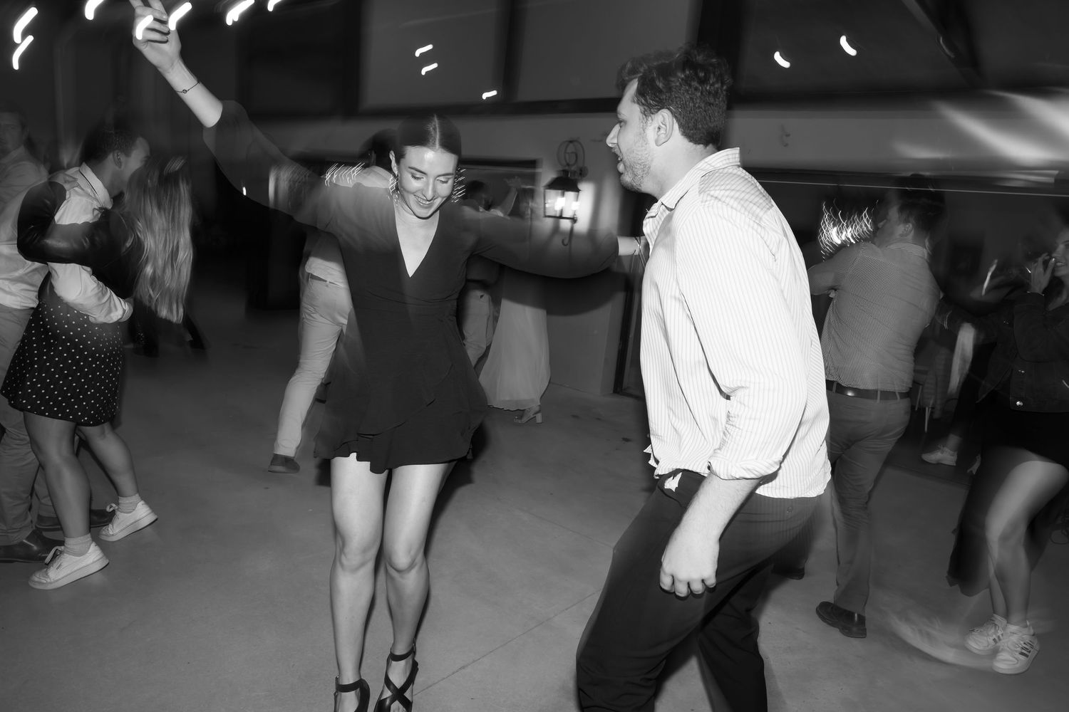 A group of people dancing together in a social dance class setting on a wooden floor.