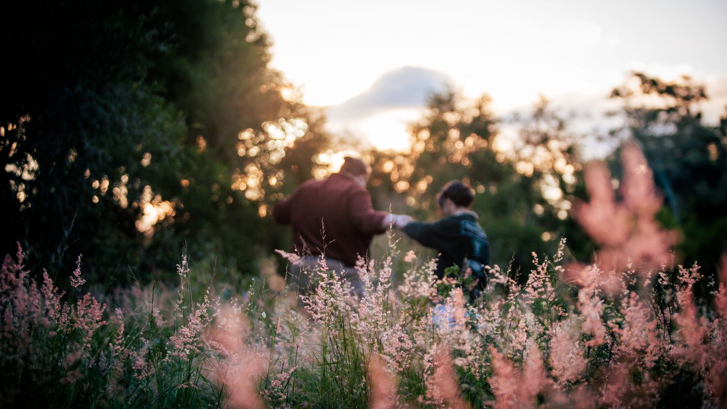 a couple look dance in the long grass at their playful pre wedding photoshoot