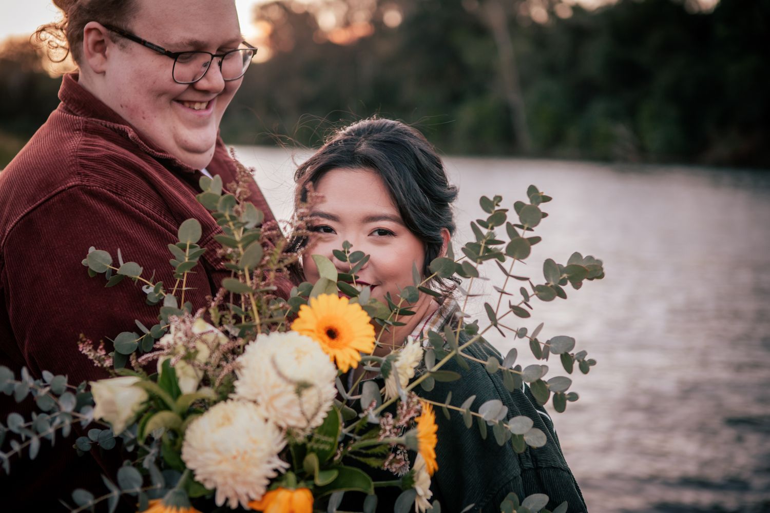 a couple look lovingly at each other at their pre wedding photoshoot. The bride-to-be holds a bouquet of flowers