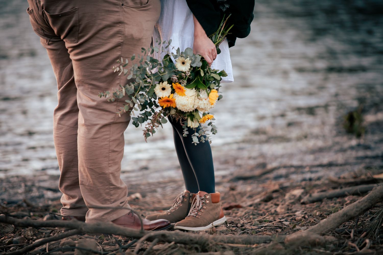 a couple look lovingly at each other at their pre wedding photoshoot. The bride-to-be holds a bouquet of flowers