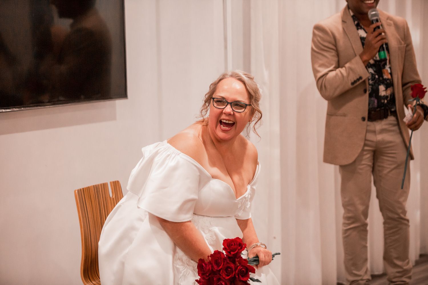 a bride laughs while listening to speeches at her reception