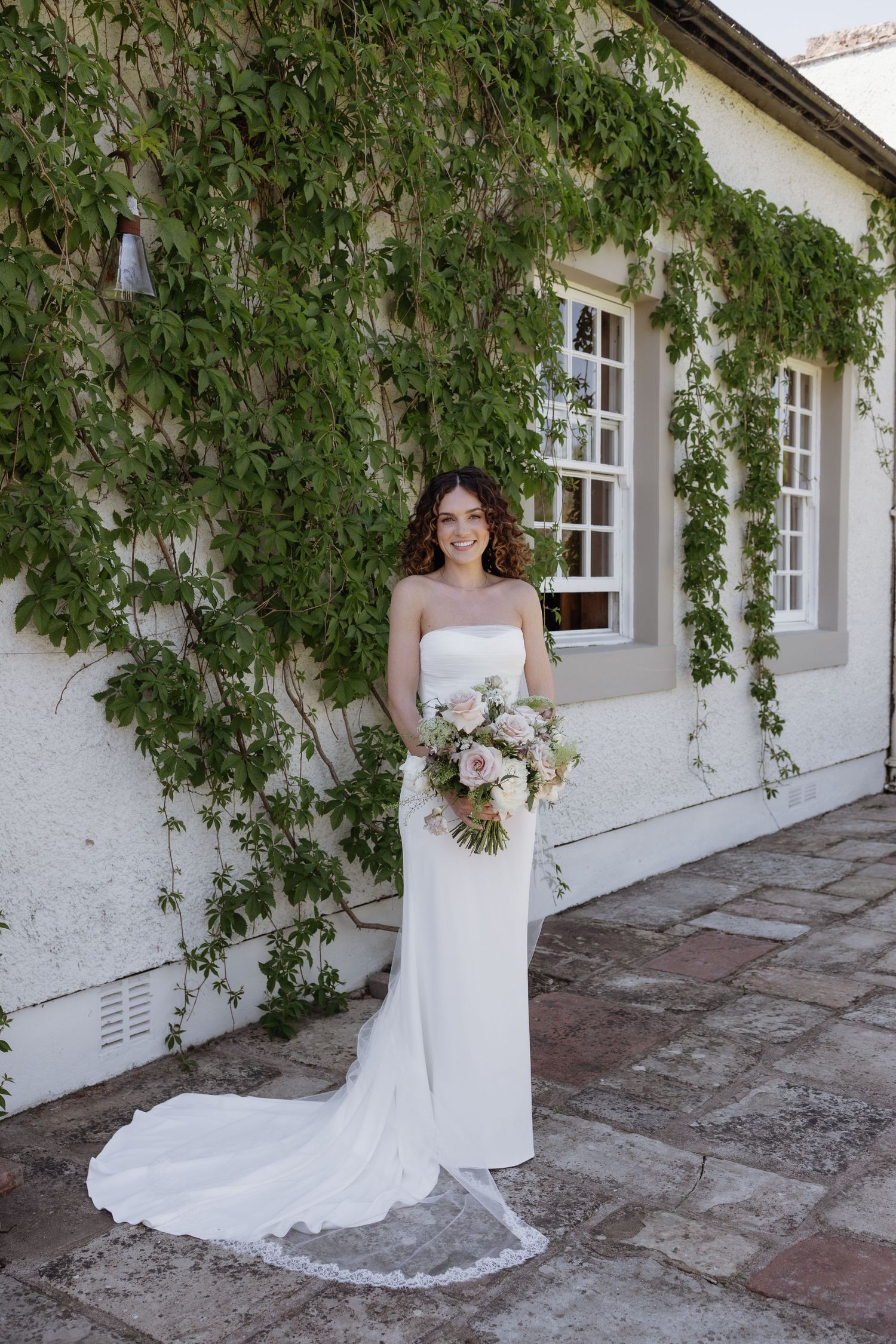 Bride standing in front of Holesfoot farmhouse in soft natural light