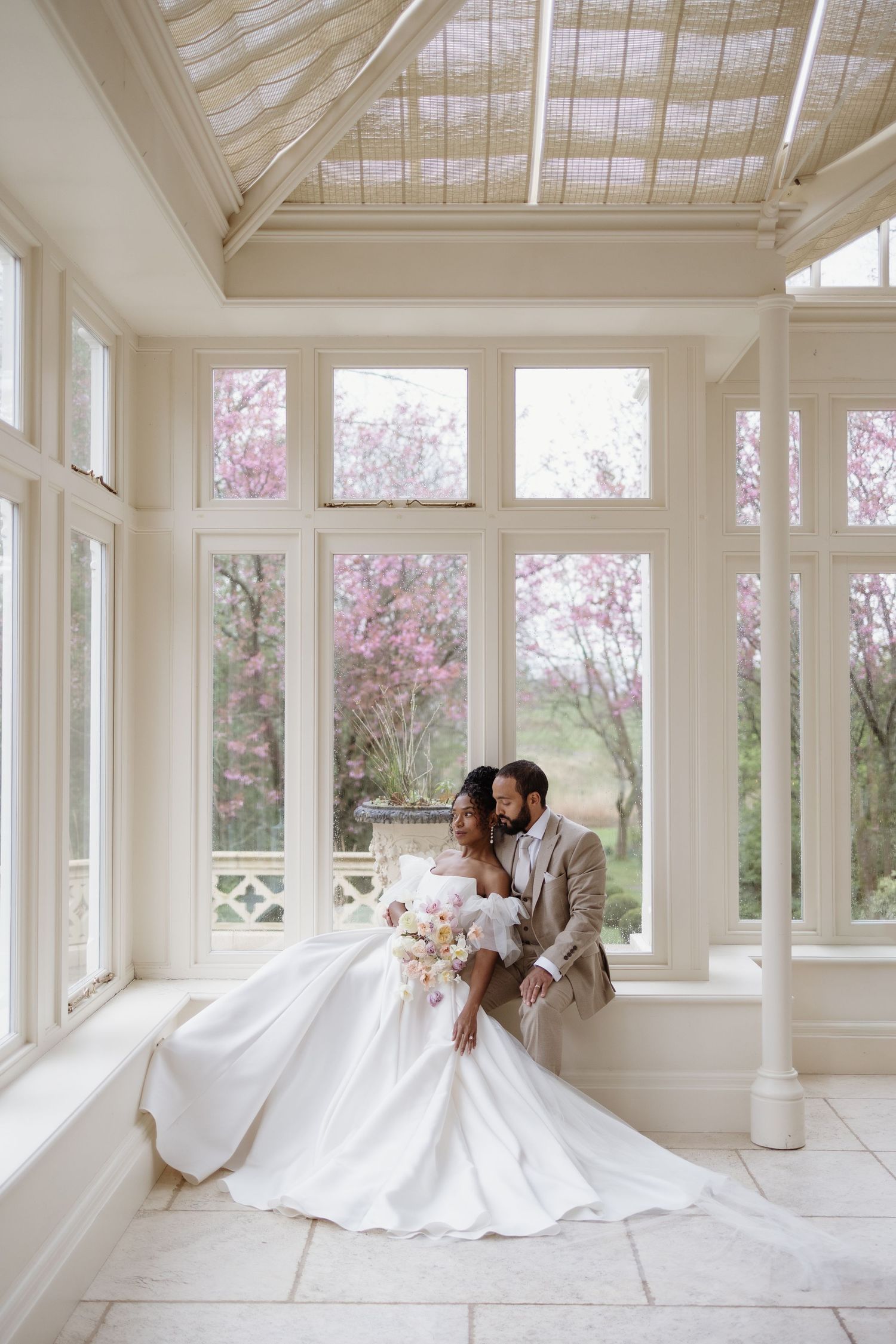 Couple sat in the orangery at Casterton Grange. Soft florals and spring light