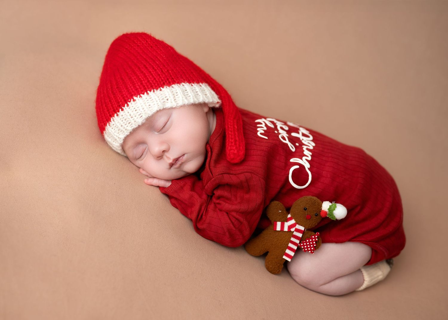 Newborn photography in Gravesend Kent with baby wearing red outfit sleeping in studio setup