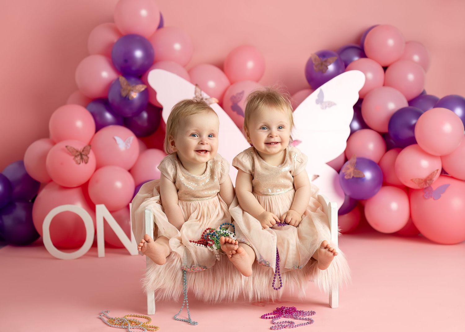 Cake smash photography session in Gravesend Kent with twins celebrating first birthday with pink balloon setup