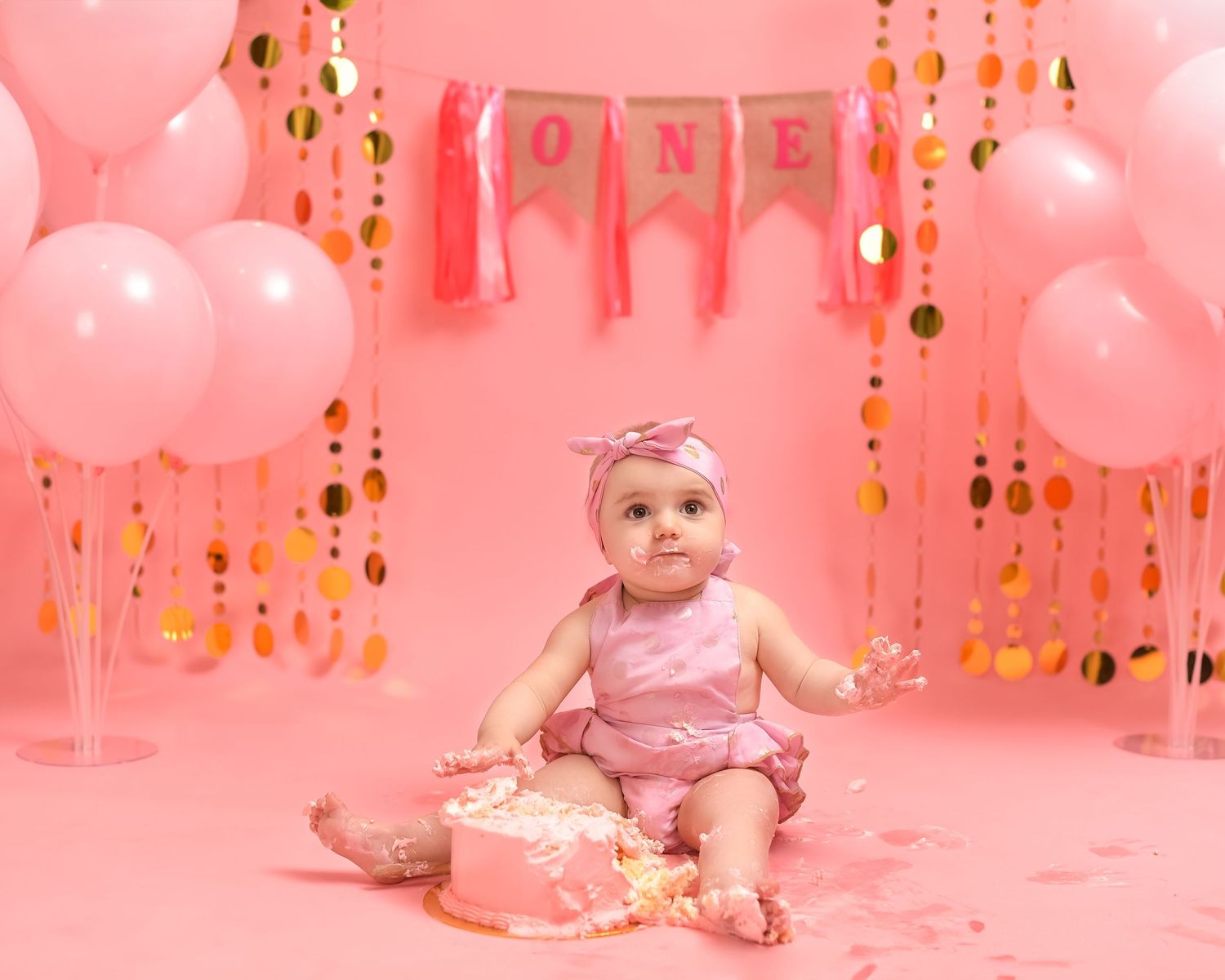 Cake smash photography session in Gravesend Kent with baby sitting in pink balloon first birthday setup