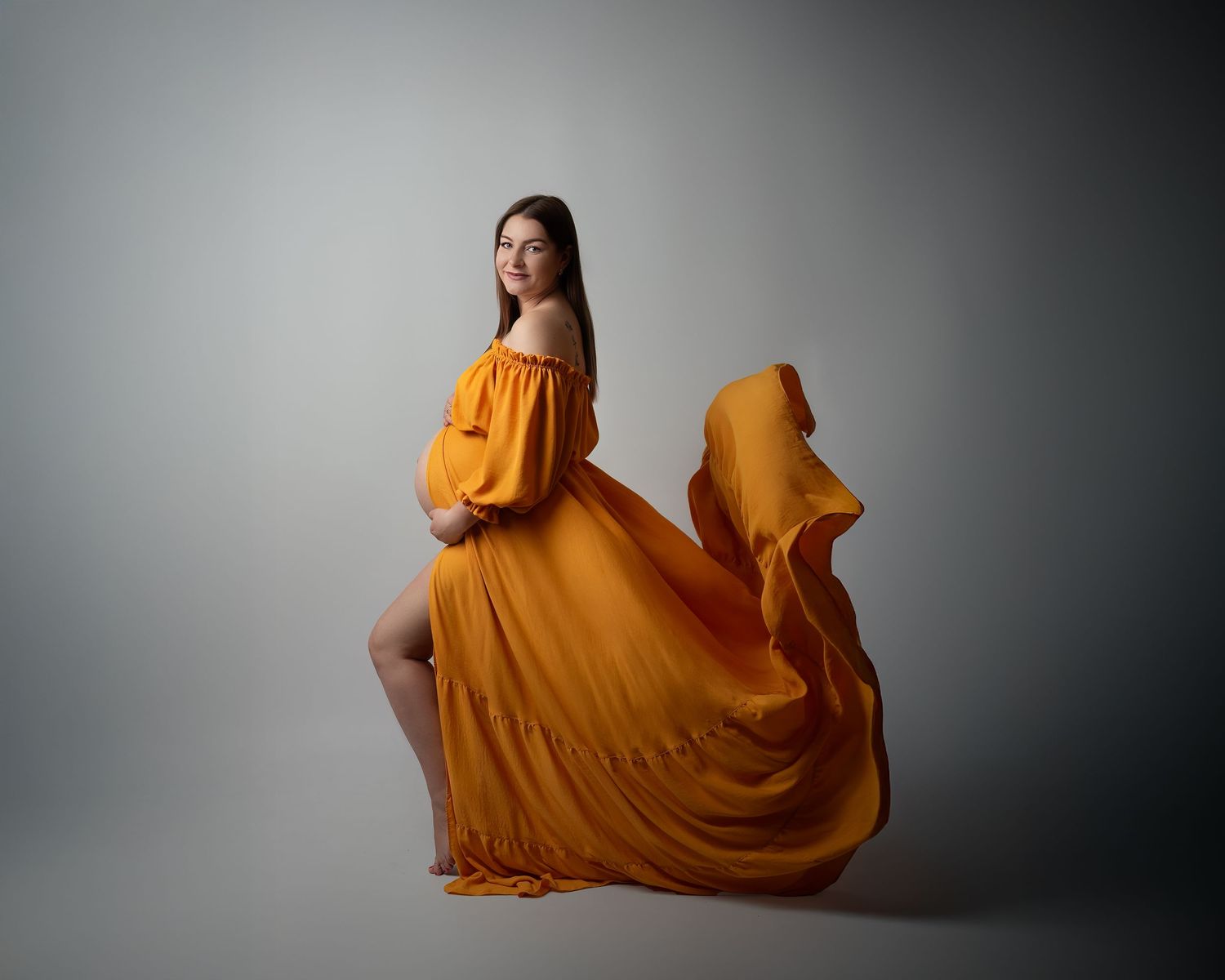 Maternity photography session in Gravesend Kent with pregnant woman in mustard yellow flowing dress in studio