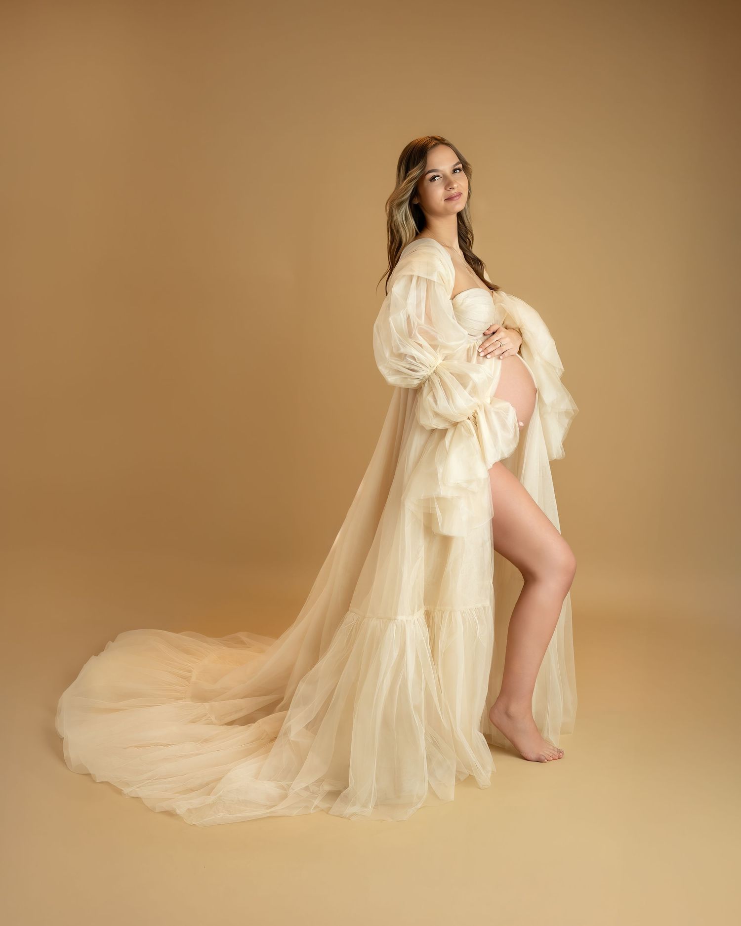 Maternity photoshoot in Gravesend Kent with pregnant woman in beige flowing dress posing in studio
