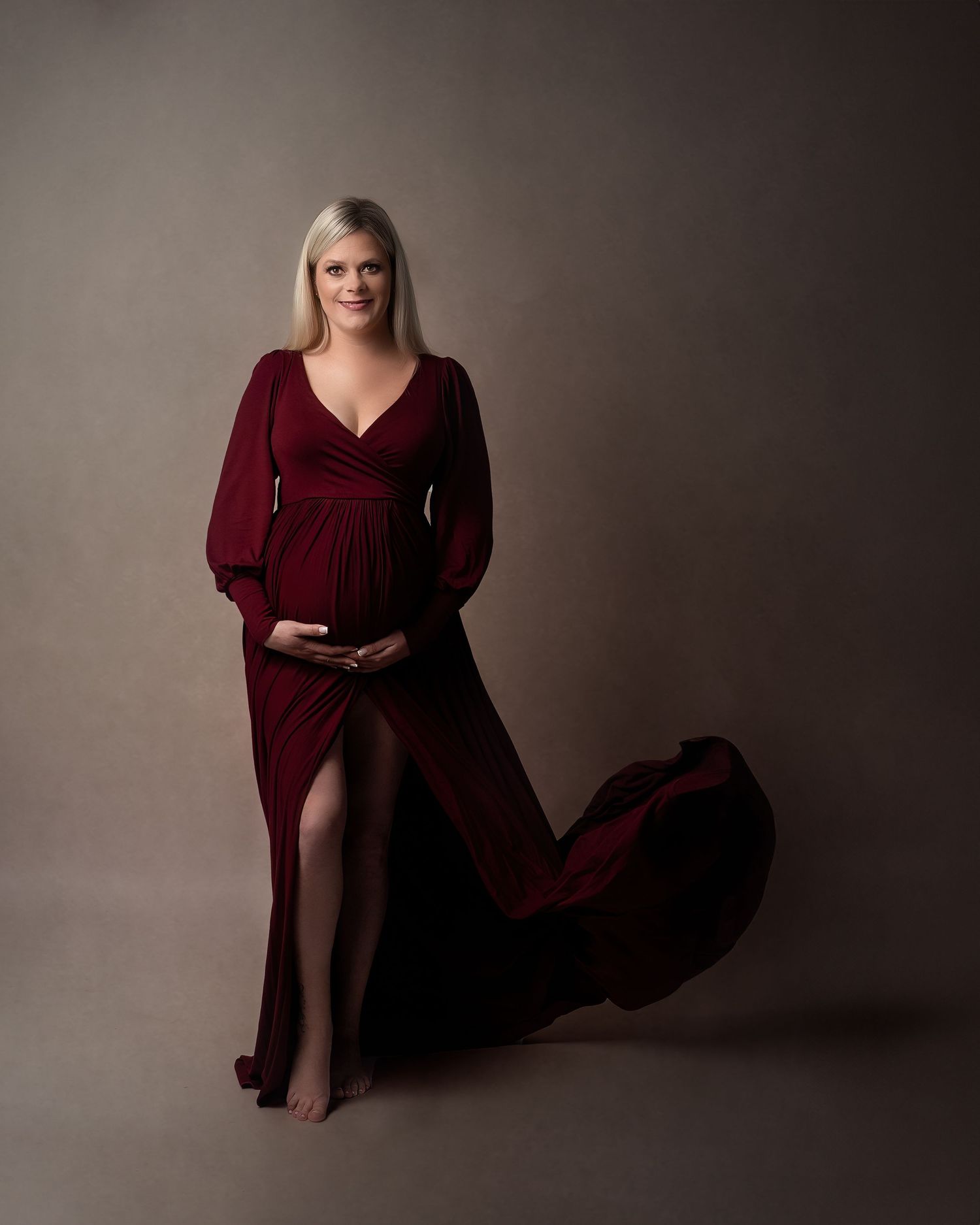 Maternity photoshoot in Gravesend Kent with pregnant woman in burgundy dress posing in studio