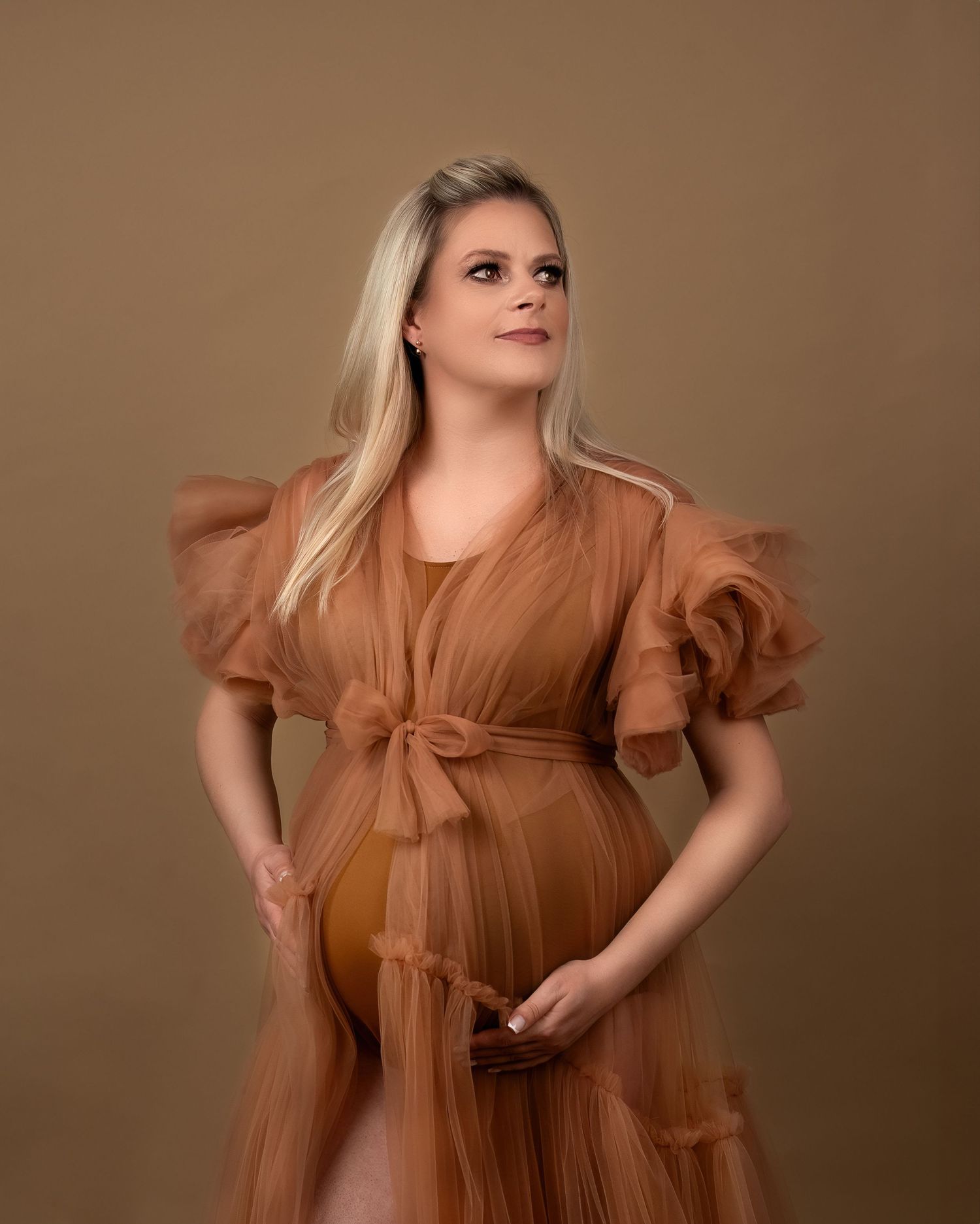 Maternity photography session in Gravesend Kent with pregnant woman in brown dress posing in studio