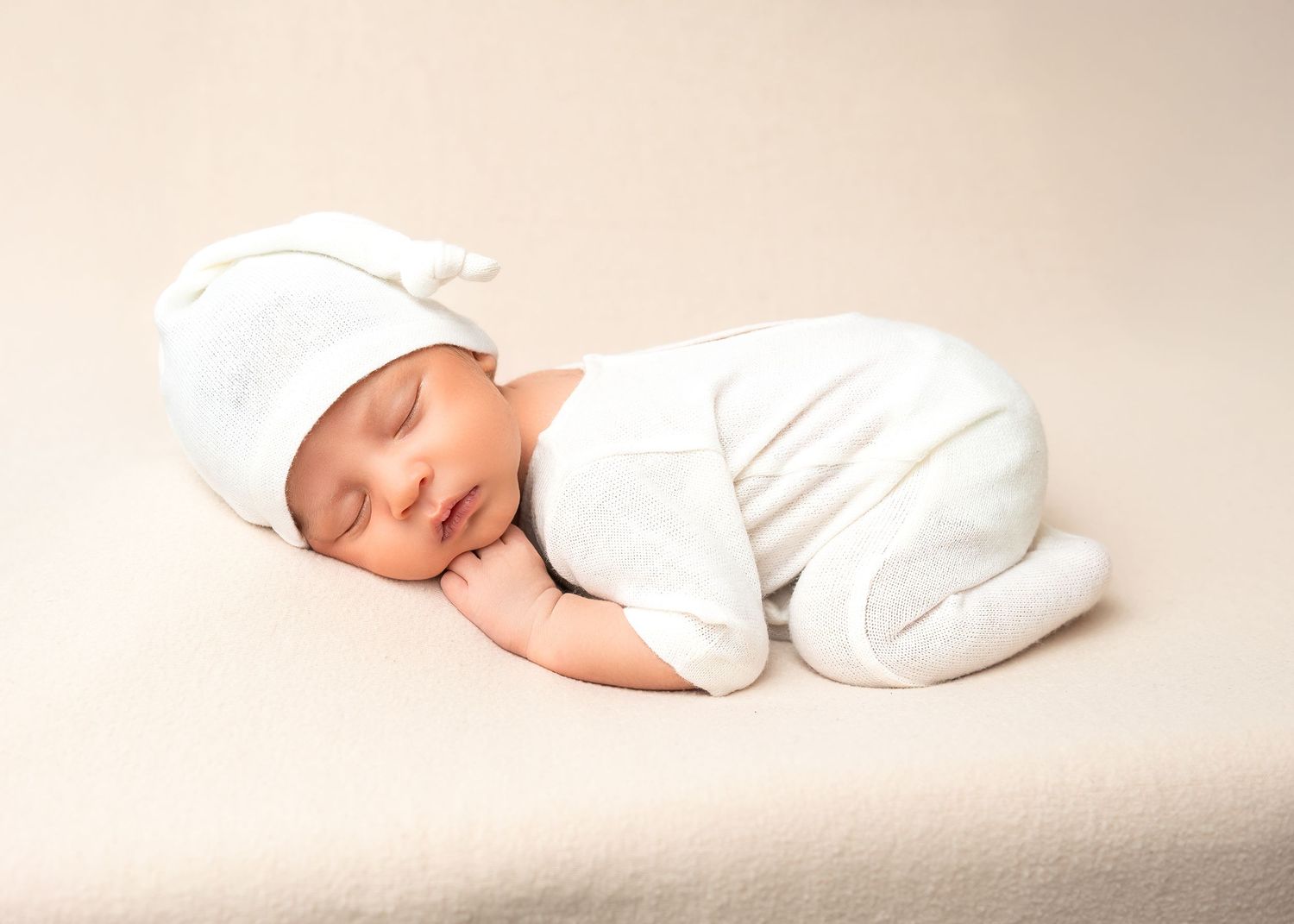 Newborn photography in Gravesend Kent with baby wearing white outfit sleeping on soft blanket