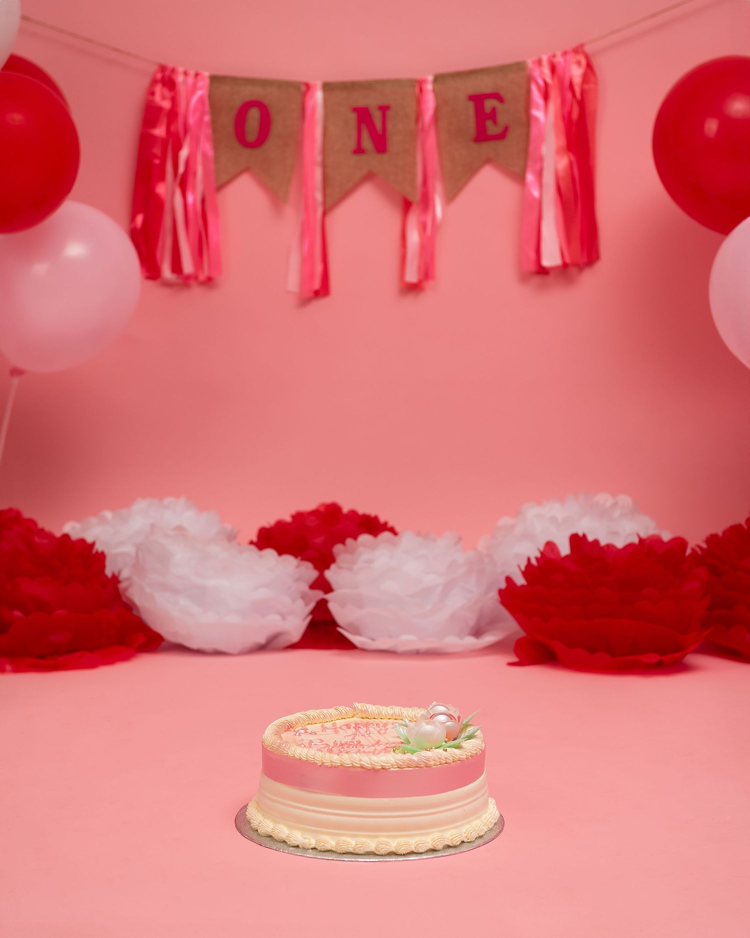 Cake smash photography in Gravesend Kent with pink and red balloon first birthday setup and cake