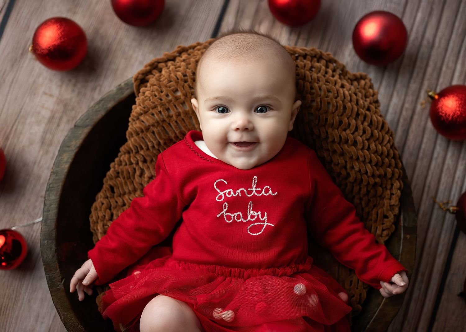 Newborn photography in Gravesend Kent with baby in red outfit sitting in basket with Christmas decorations