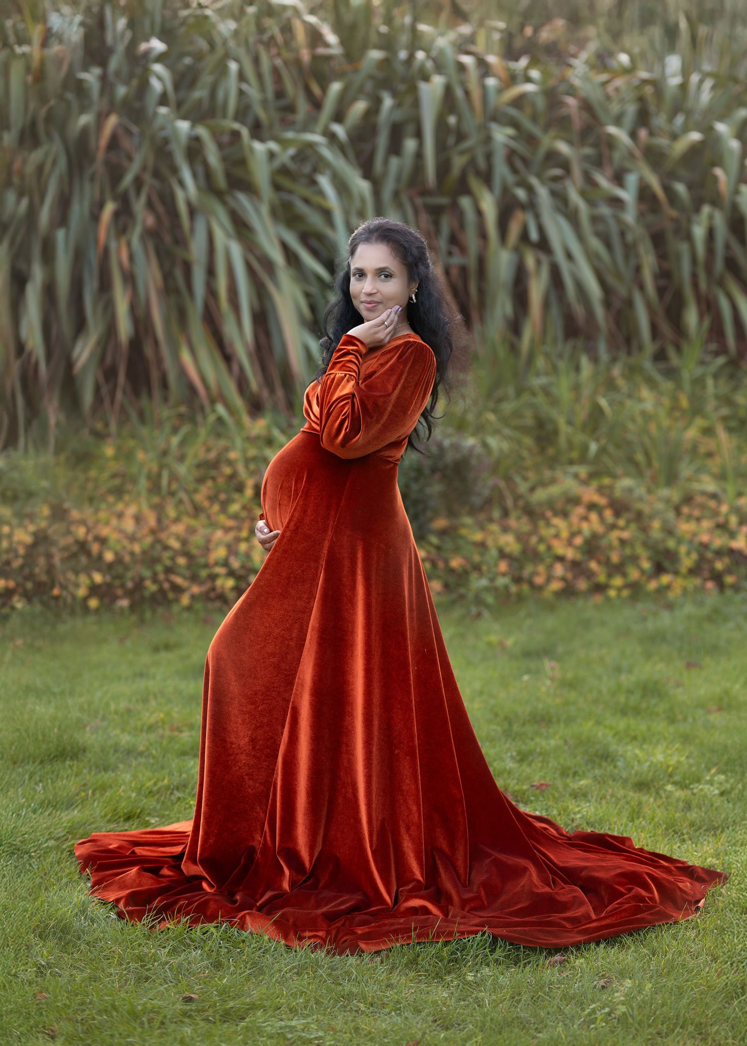 Outdoor maternity photoshoot in Gravesend Kent with pregnant woman in red dress standing in nature