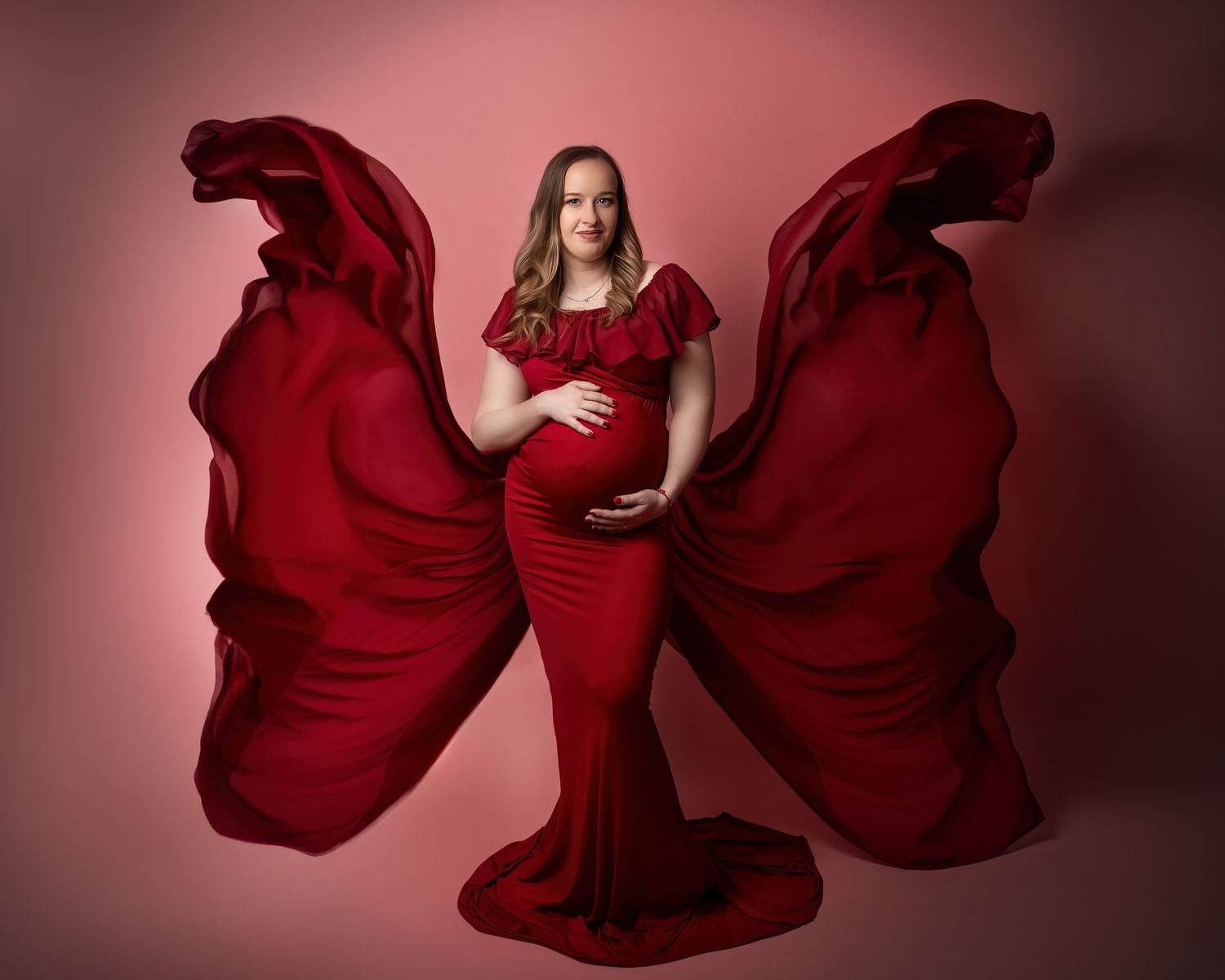 Maternity photography session in Gravesend Kent with pregnant woman in red flowing gown with dramatic fabric in studio
