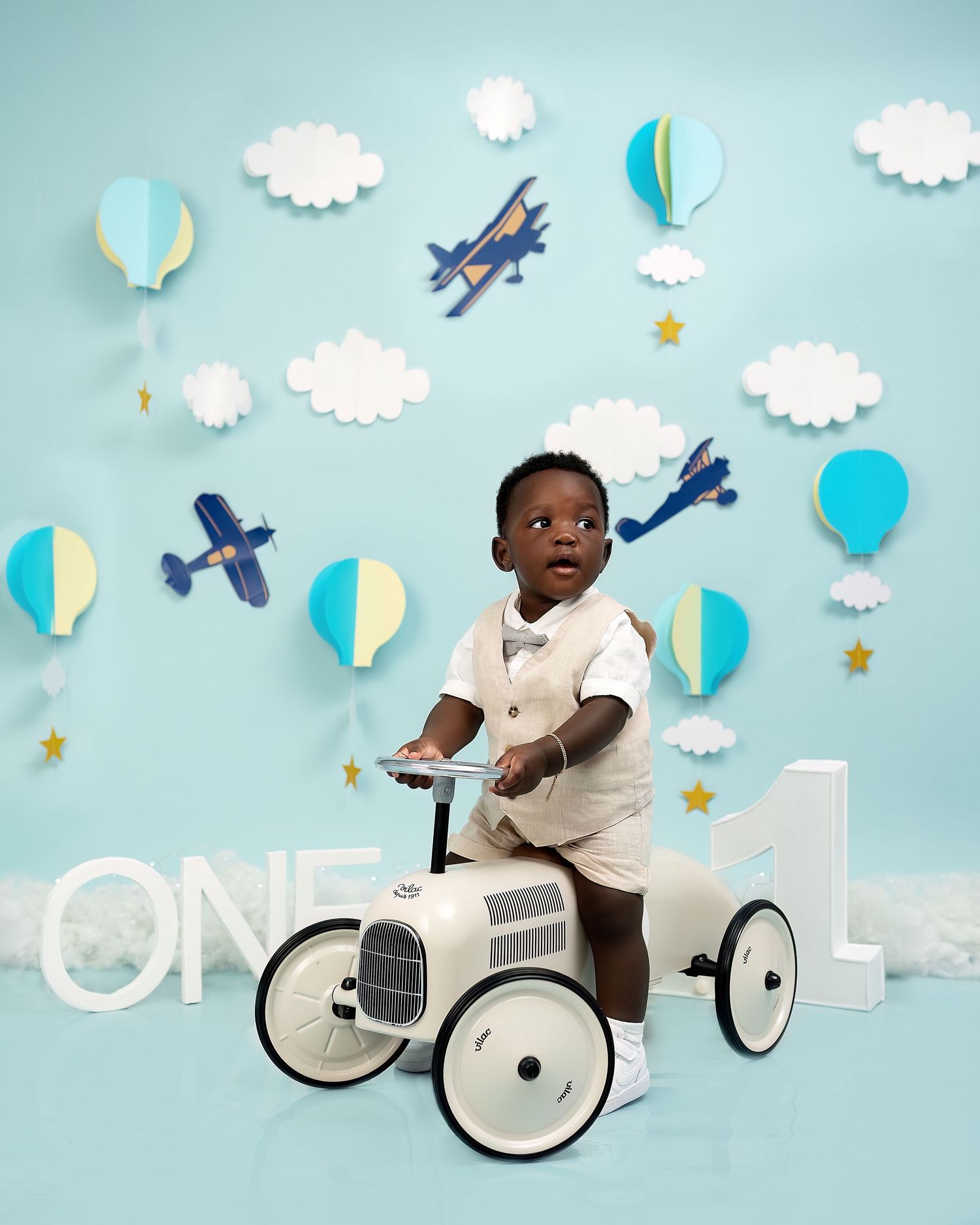 Cake smash photoshoot in Gravesend Kent with baby sitting on toy car with blue themed background