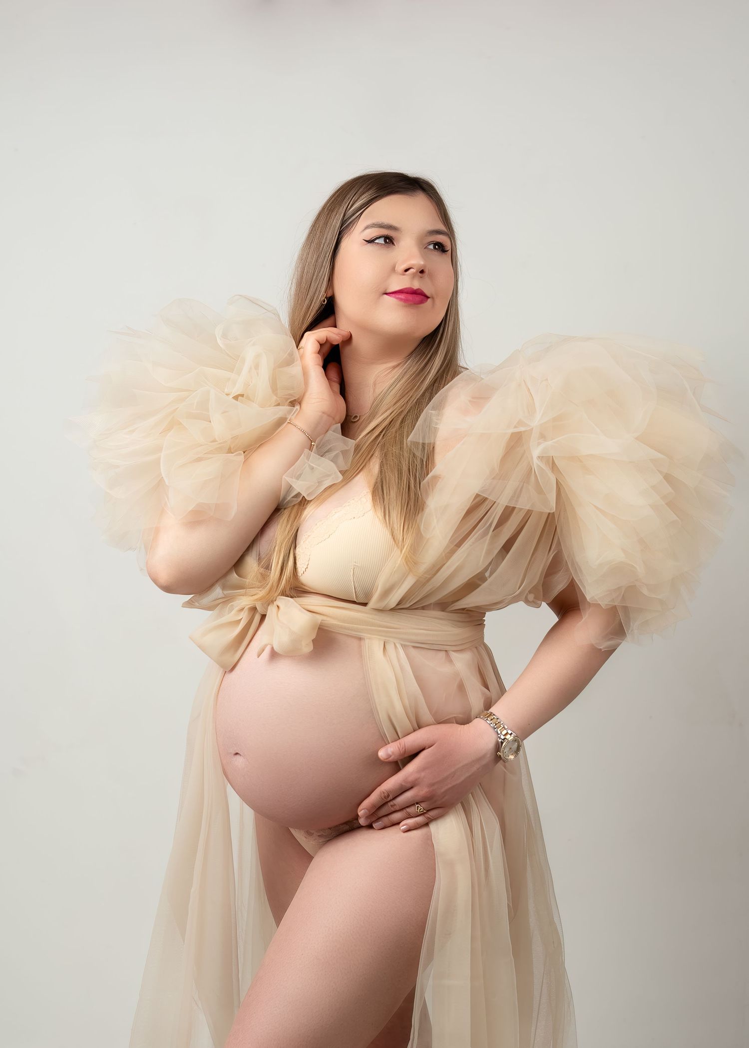 Maternity photography in Gravesend Kent with pregnant woman in soft beige dress with feather details in studio