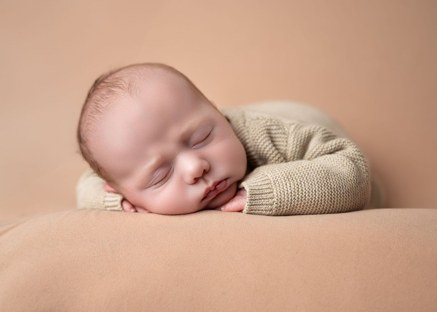 Newborn photography in Gravesend Kent with baby sleeping on soft beige background close up portrait