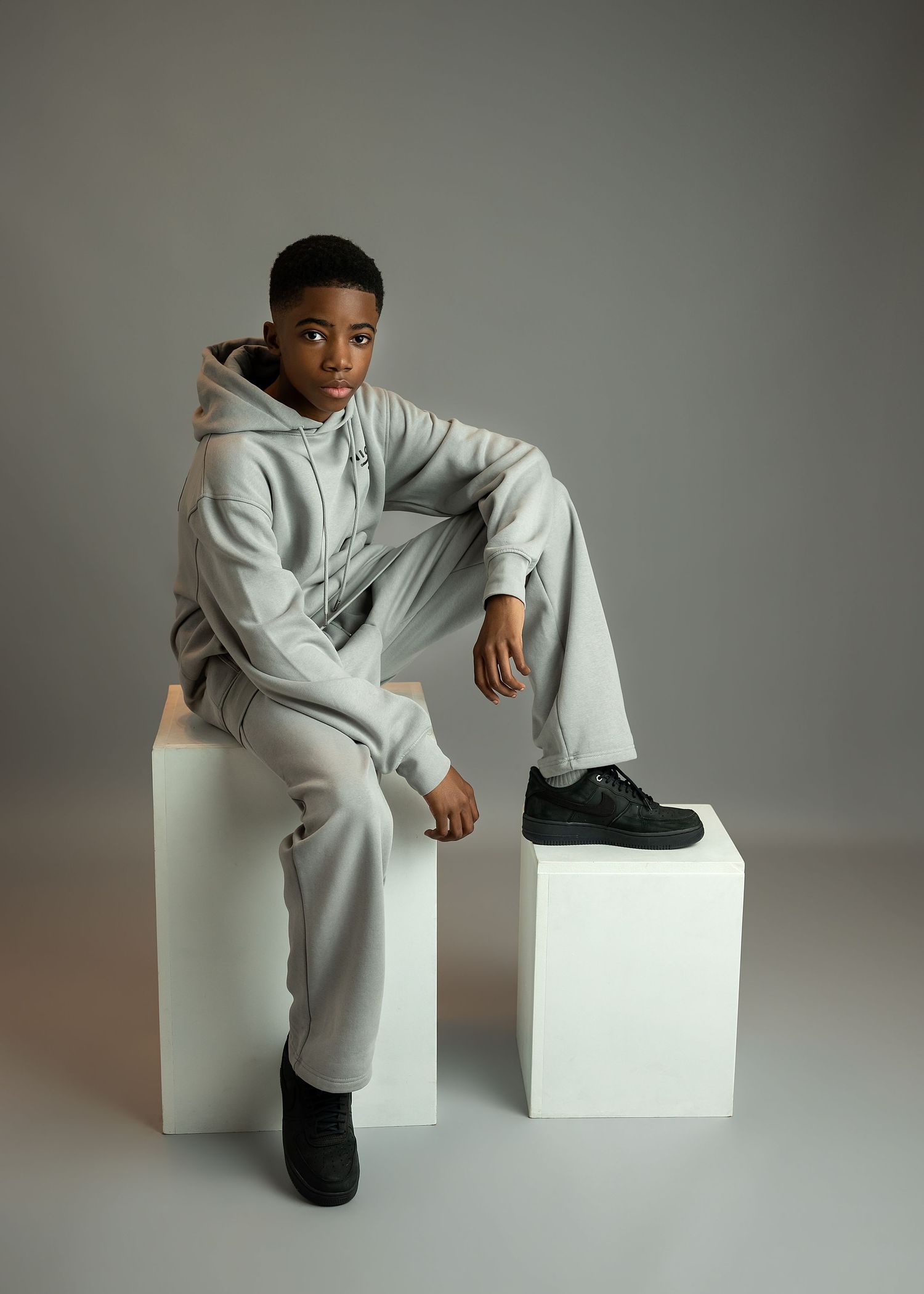 Portrait photography session in Gravesend Kent with man in light outfit posing on cube in studio