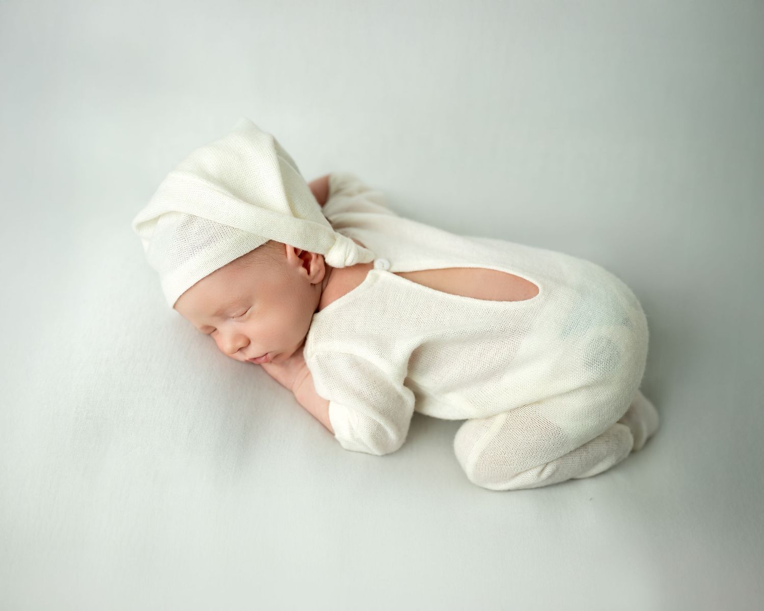 Newborn photoshoot in Gravesend Kent with baby in white outfit sleeping on soft grey background