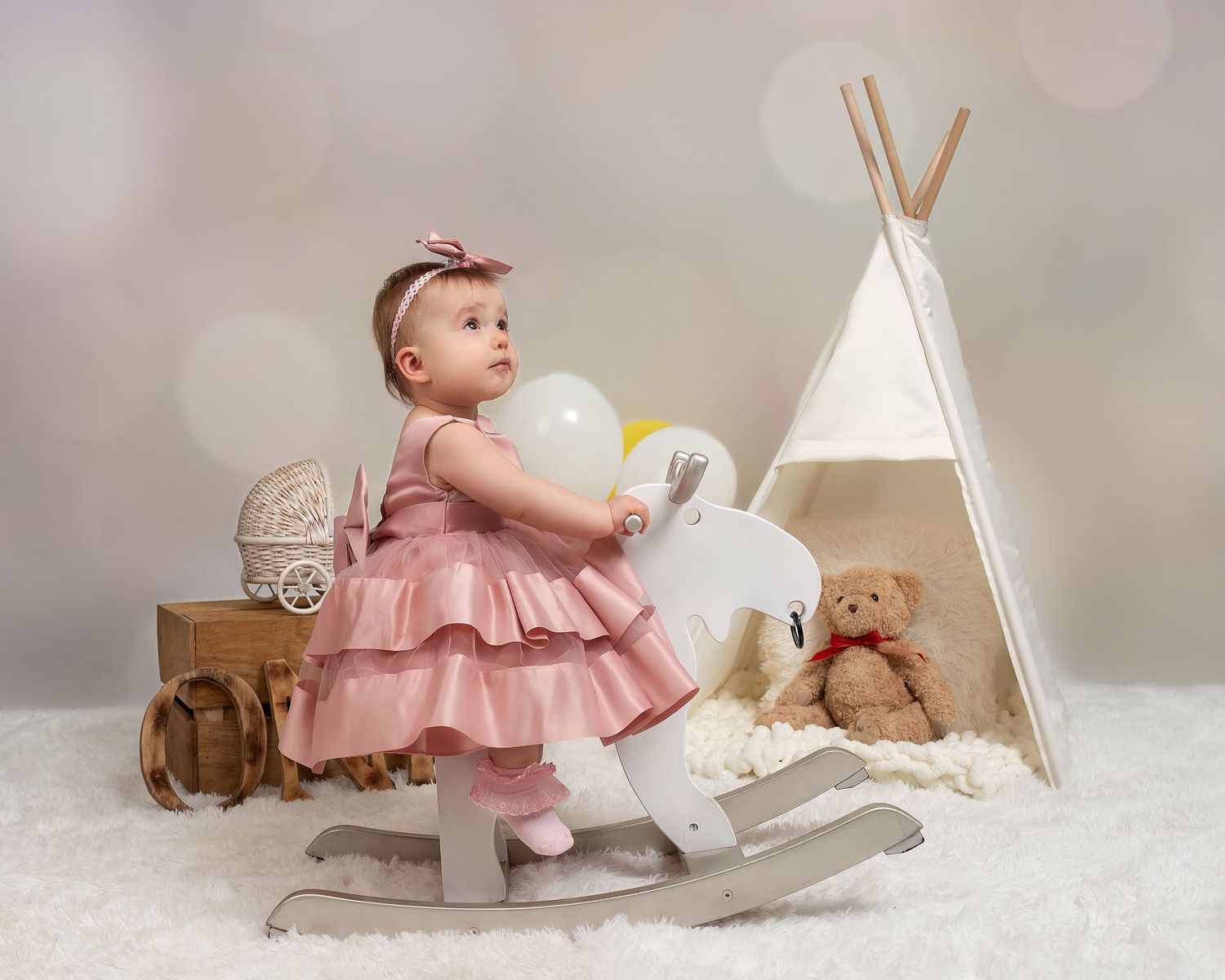 Children photography session in Gravesend Kent with baby girl in pink dress sitting in studio with teepee setup