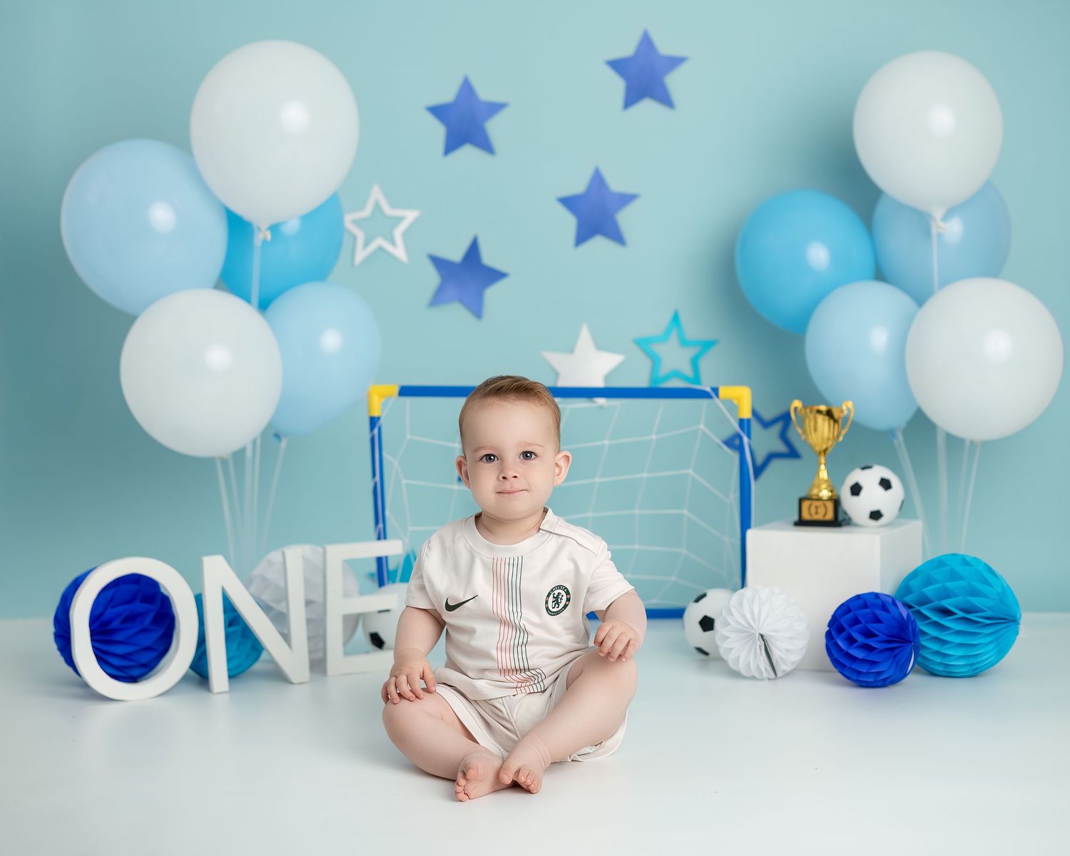 Cake smash photography session in Gravesend Kent with baby in blue first birthday setup with balloons and stars
