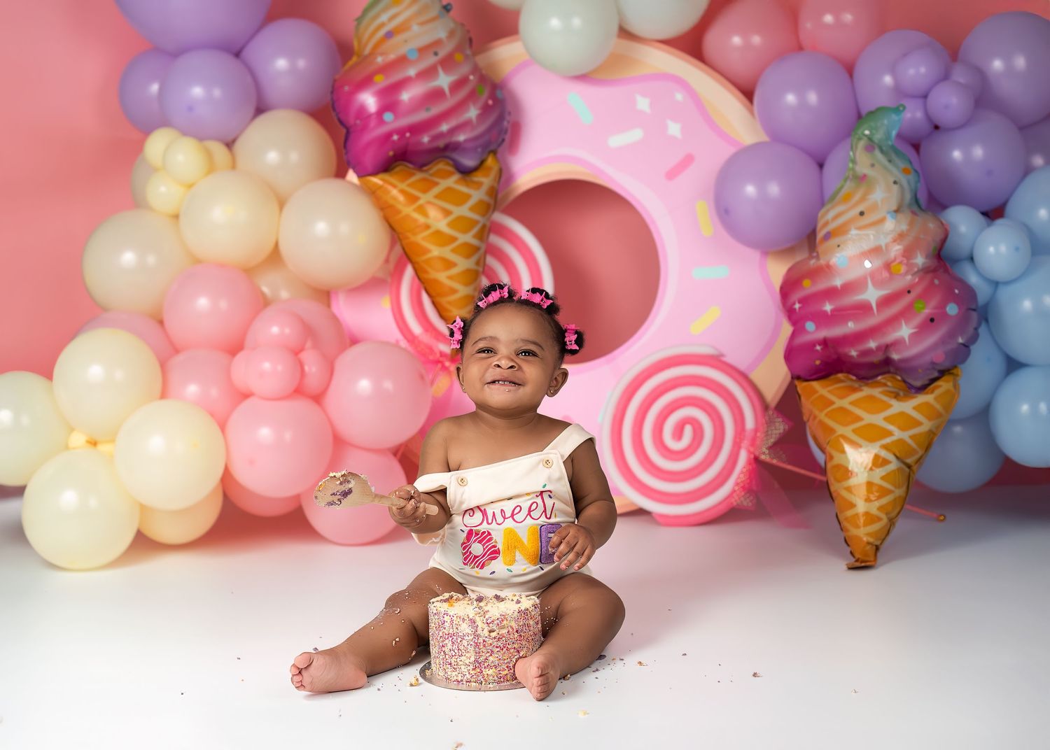 Cake smash photography session in Gravesend Kent with colourful candy themed background and balloons
