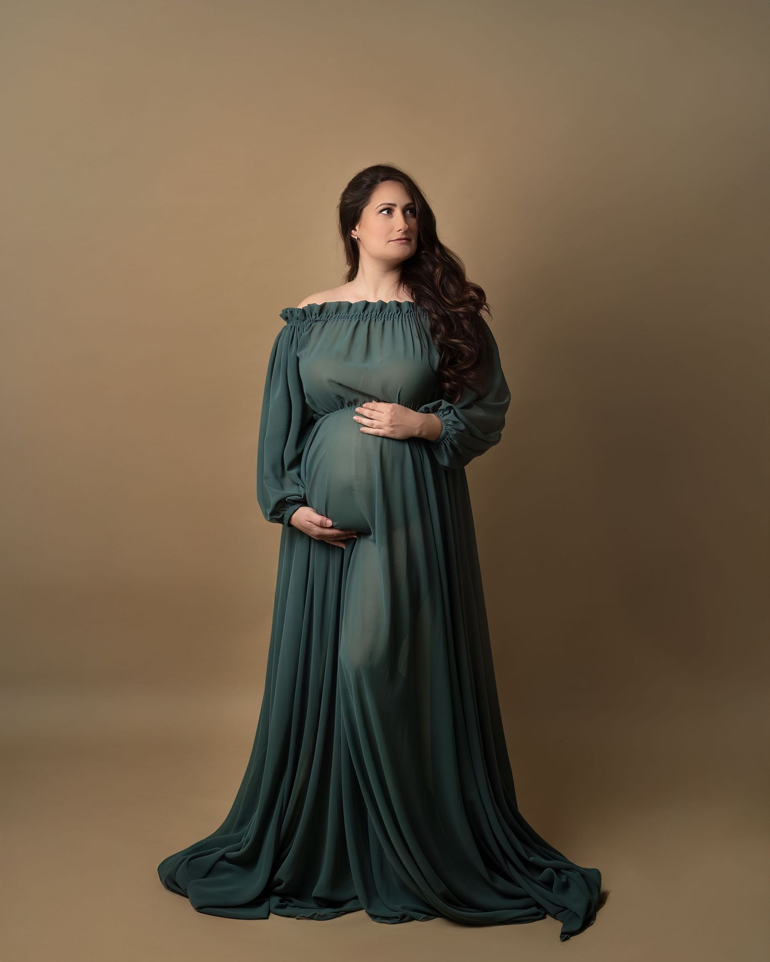 Maternity photoshoot in Gravesend Kent with pregnant woman in dark green dress posing in studio