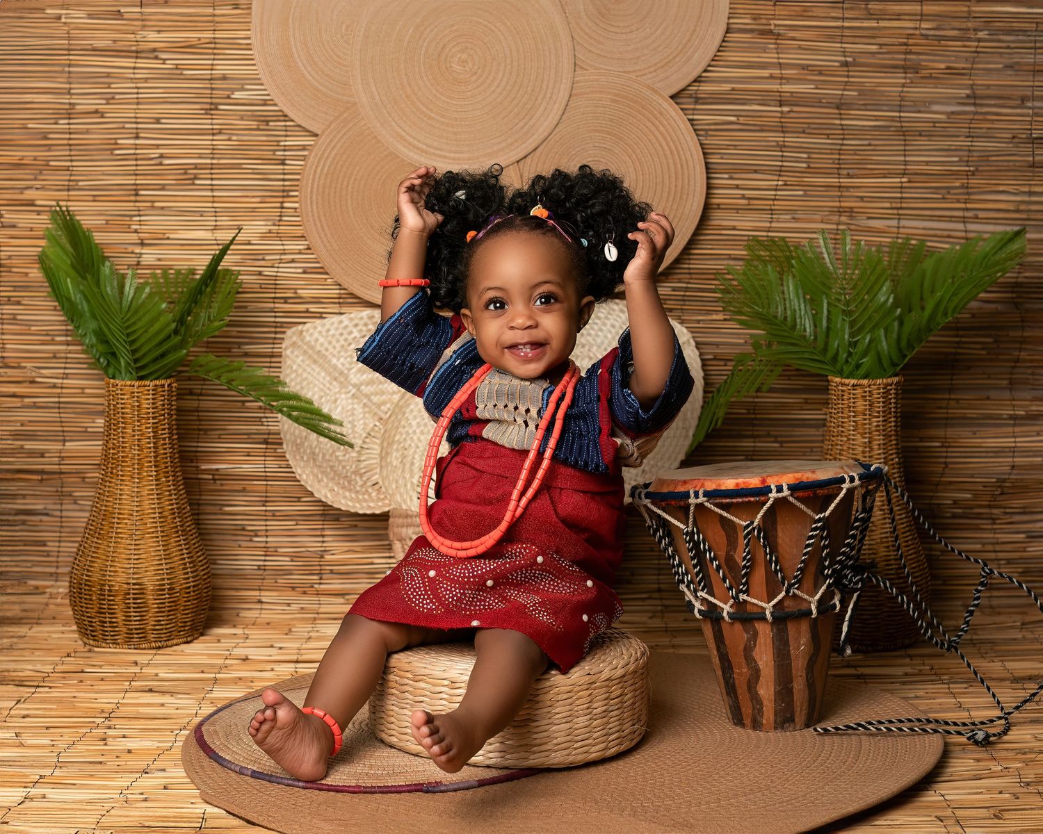 Children photography session in Gravesend Kent with baby in red outfit sitting in boho themed studio setup